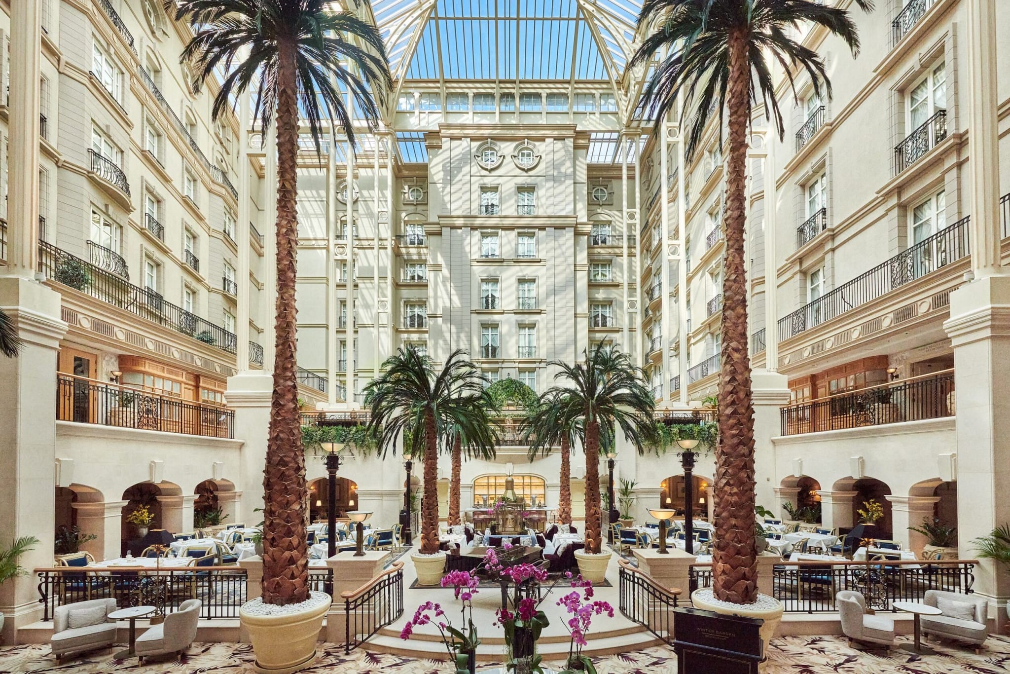 The Winter Garden at The Landmark London, a glass-roofed atrium with palms and restaurant tables