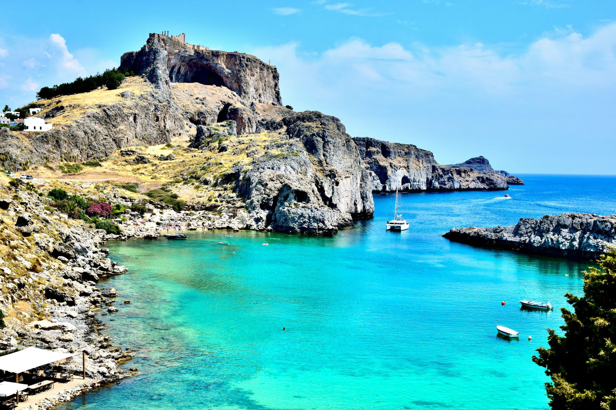 Båt i turkist vann under klippene ved Lindos på Rhodos