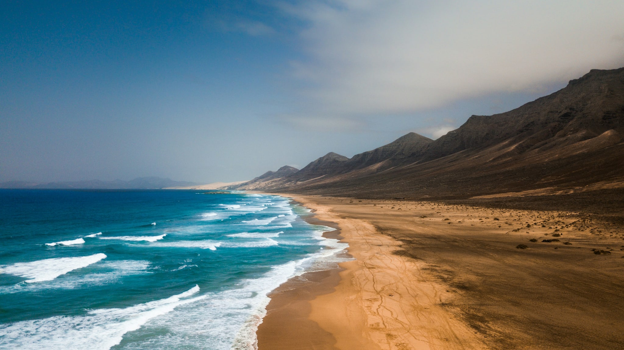 A long sandy beach beneath the mountains of Fuerteventura