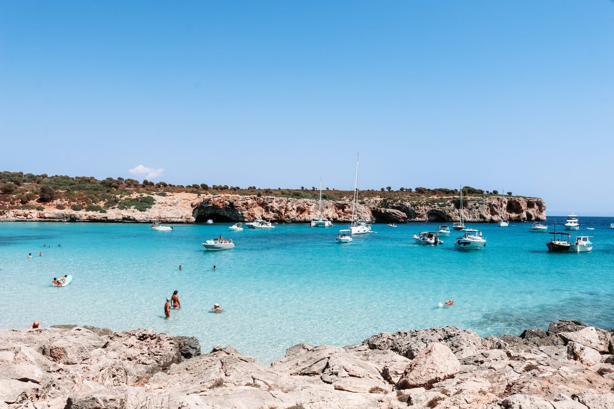 Turkis vann og ankrede seilbåter i en bukt med lave klipper på Mallorca