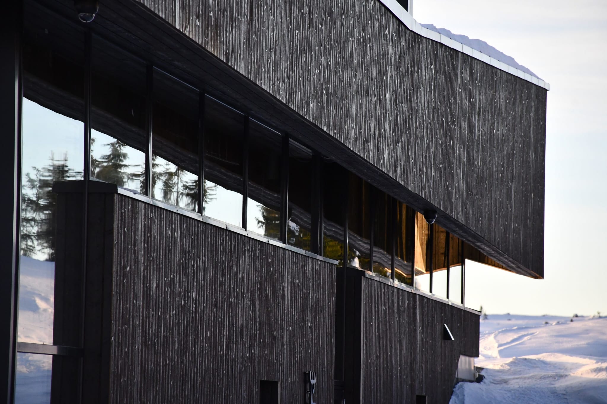 Dark timber facade of Pellestova Hotell on top of Hafjell in winter