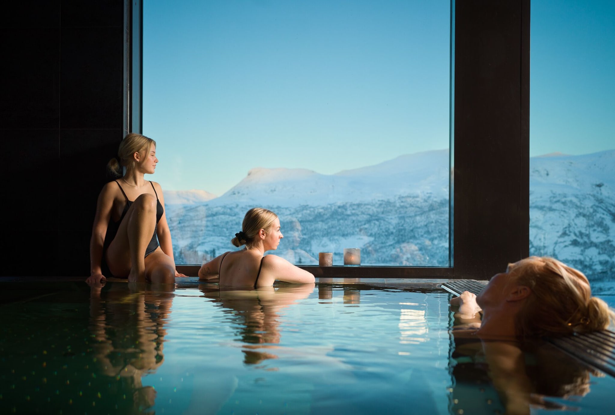 Guests in the spa pool at Skarsnuten with views of snowy mountains in Hemsedal