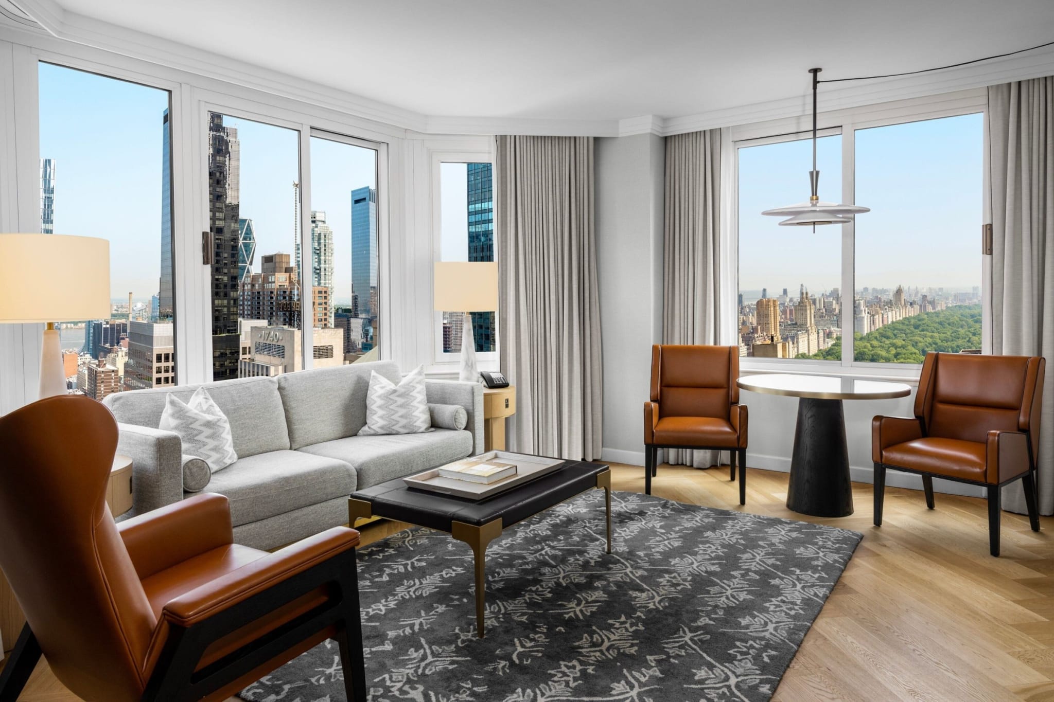 Living room of a suite at The London New York with tall windows over Midtown
