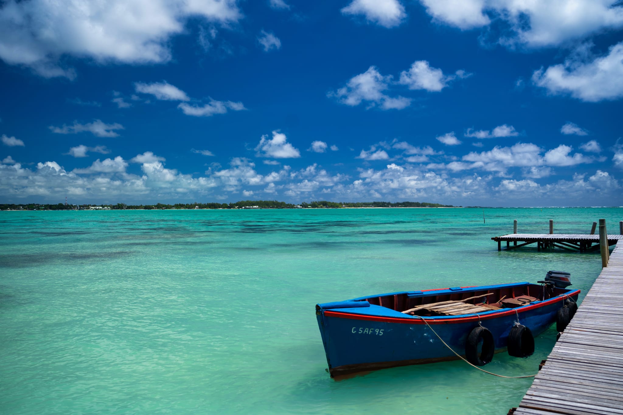 Liten båt ved en brygge i turkist vann på Mauritius