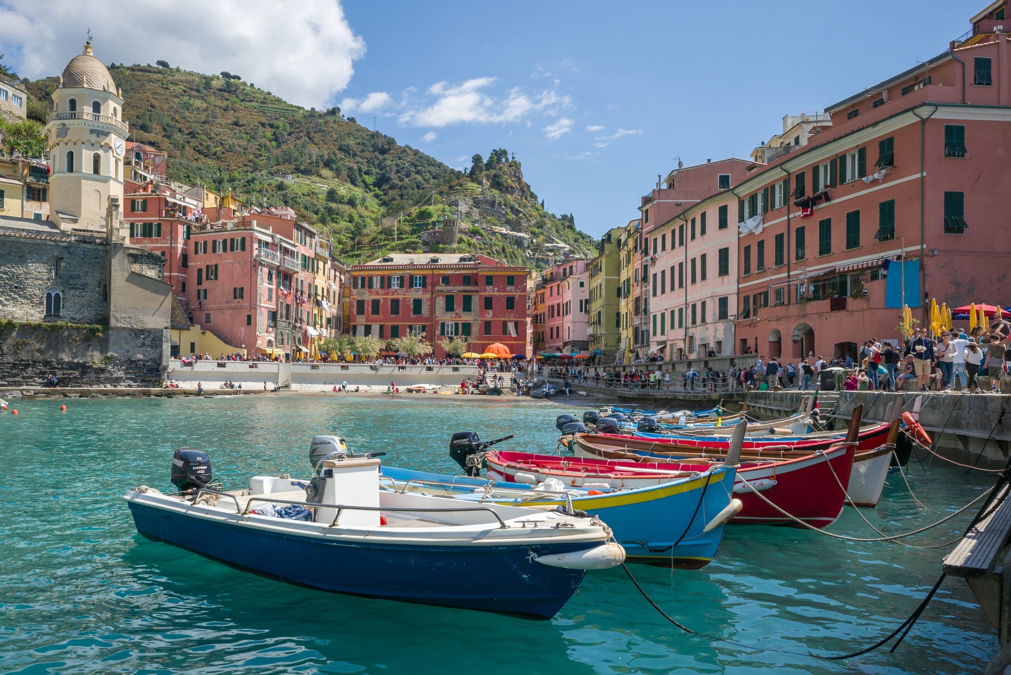 Colourful boats in the little harbour of Vernazza in the Cinque Terre, with pastel houses behind