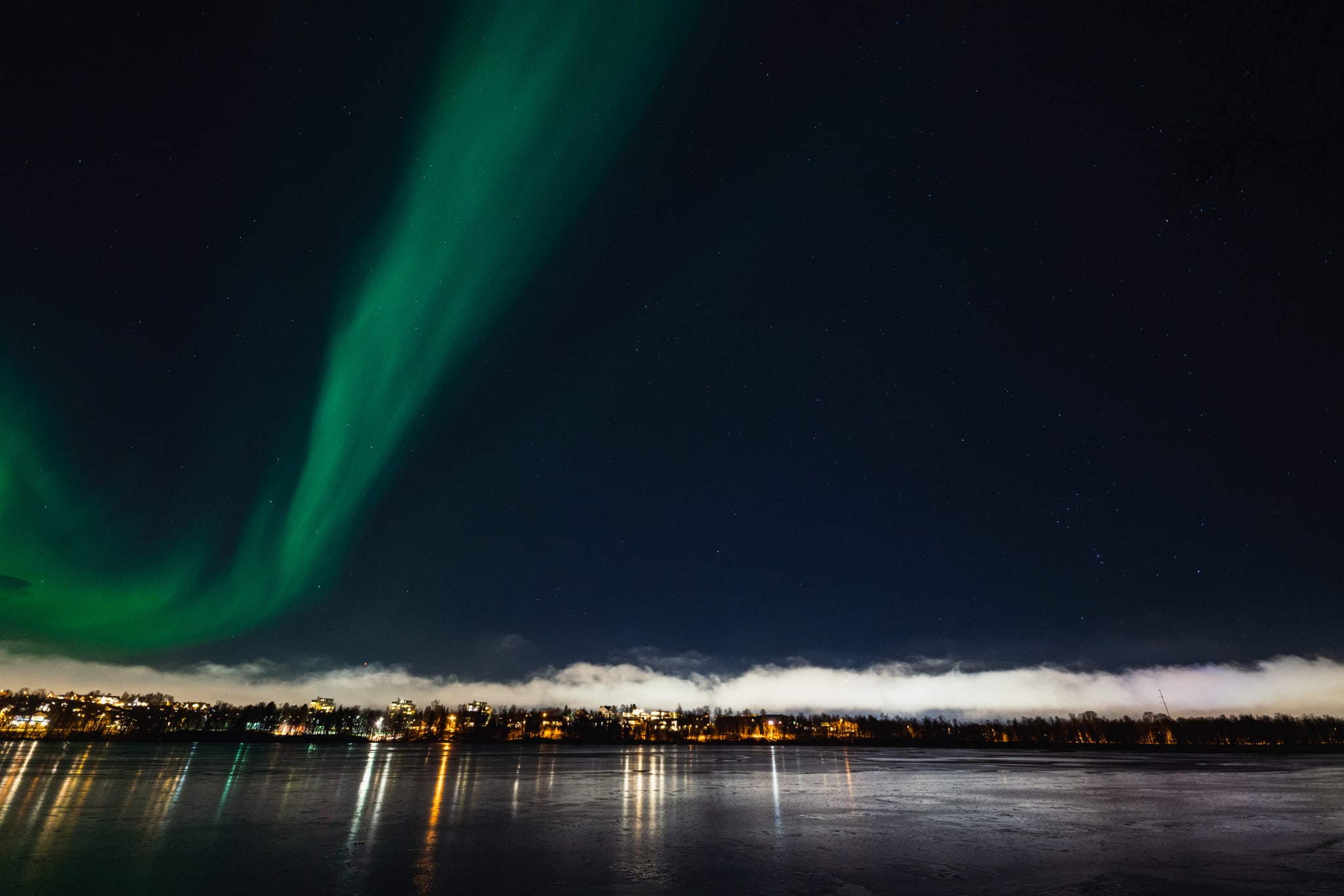 Green northern lights over Prestvannet lake in Tromsø on a winter night