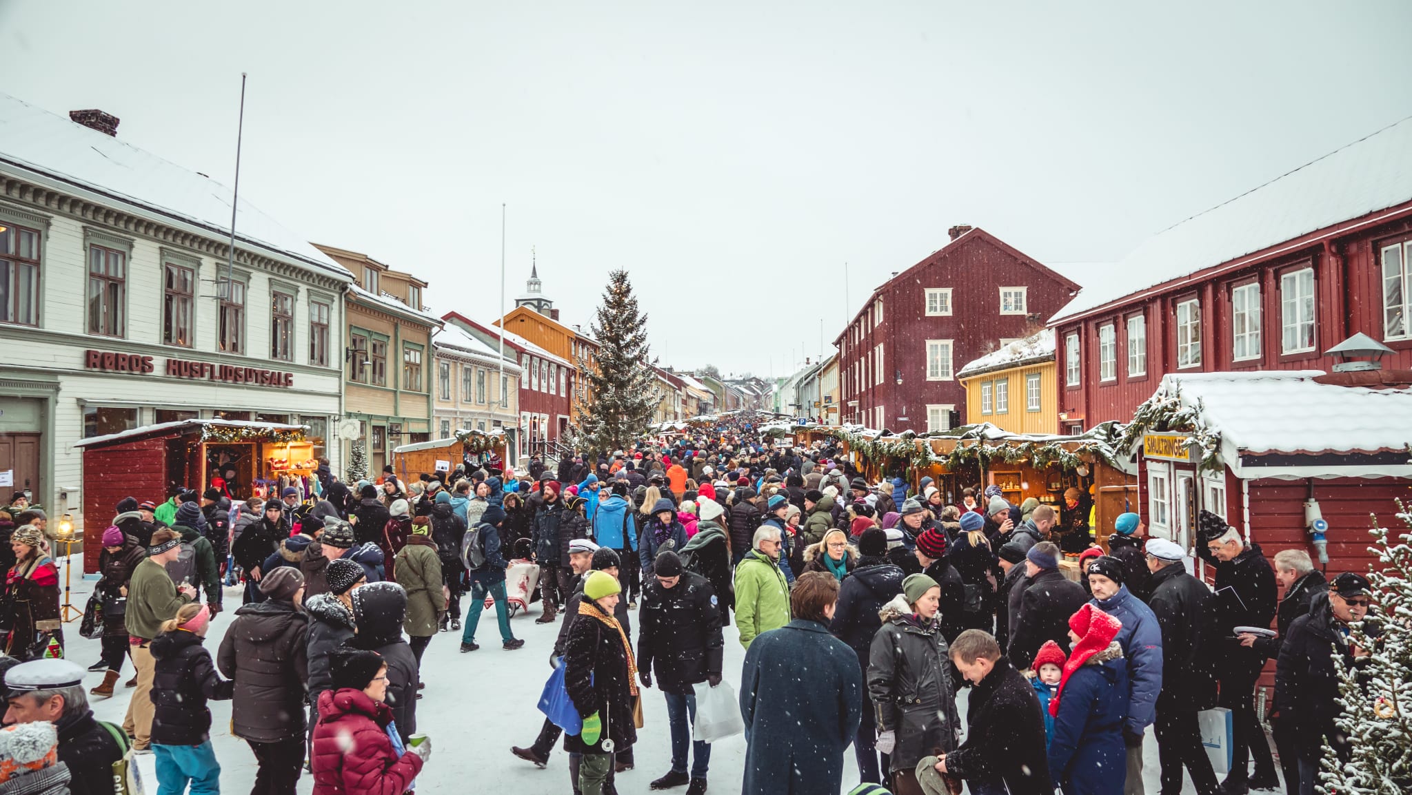 Julemarkedet i Bergmannsgata på Røros med markedsboder, snøfall og historiske trehus