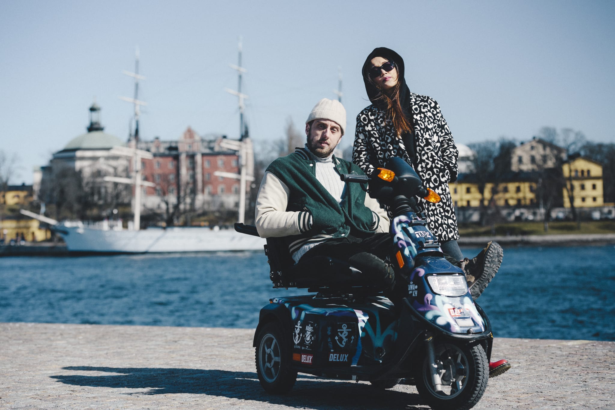 Two friends on an electric scooter on the waterfront in Stockholm on a sunny spring day