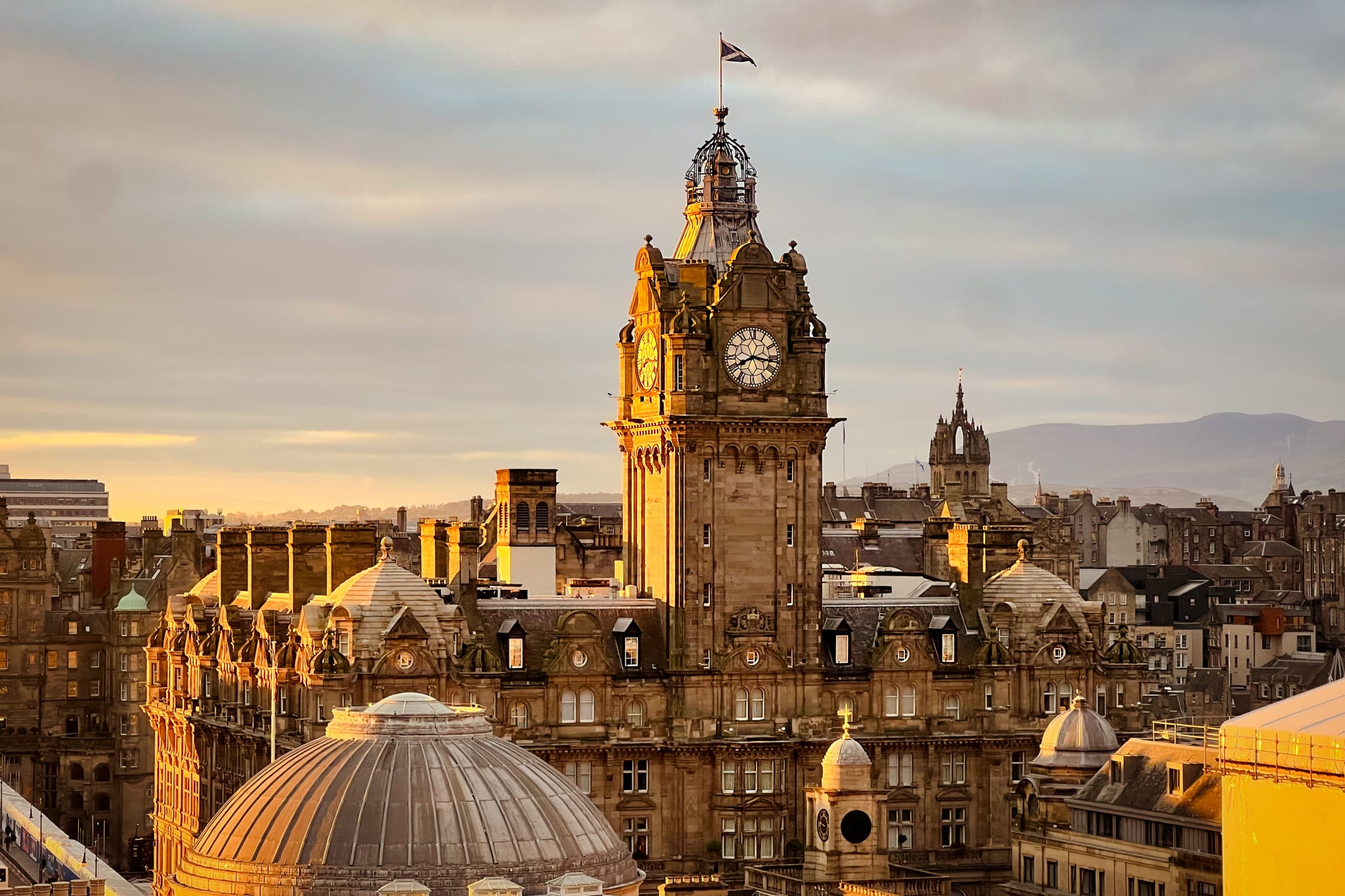 The Balmoral clock tower above the rooftops of Edinburgh in evening light