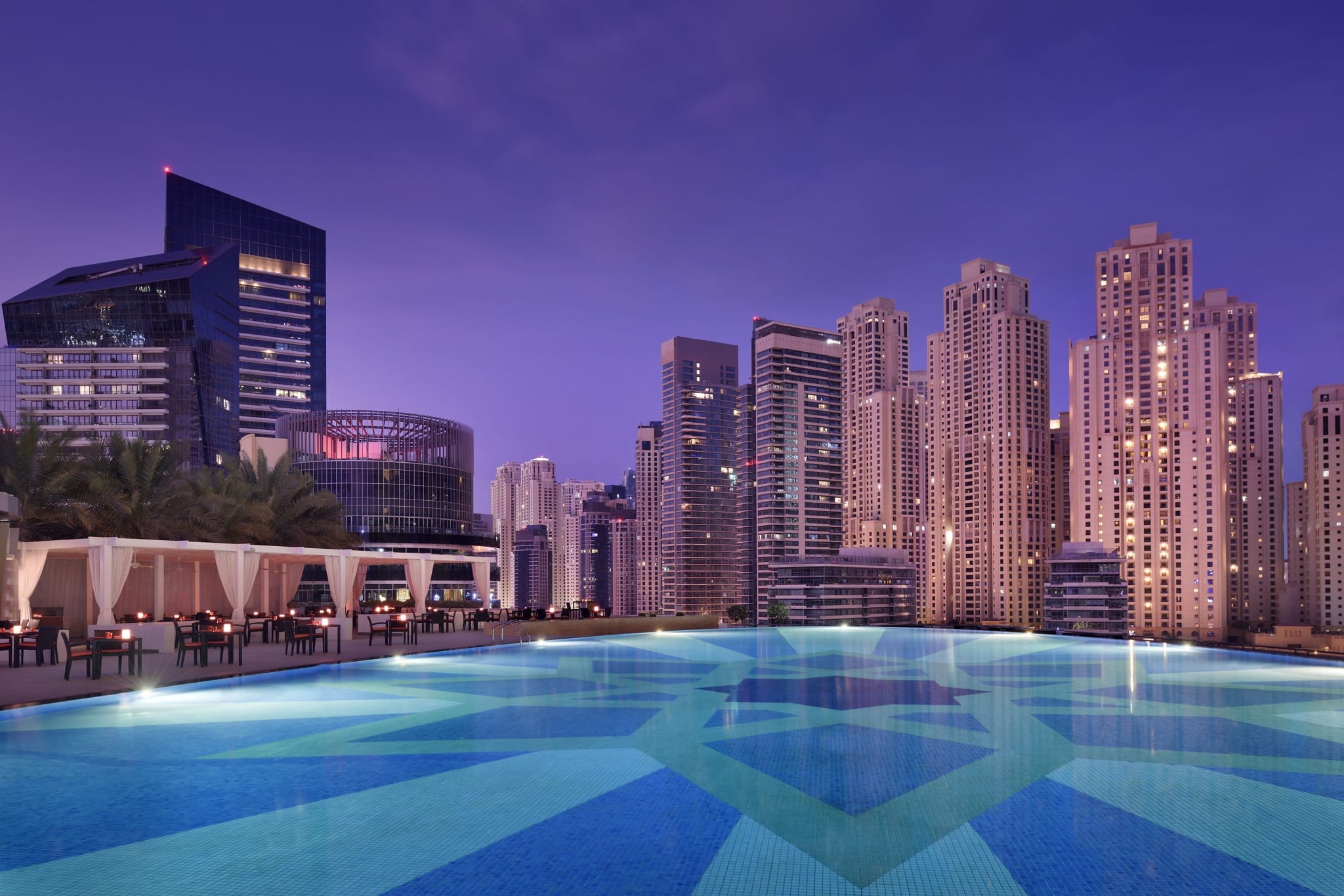 A pool overlooking the skyscrapers of Dubai Marina at night