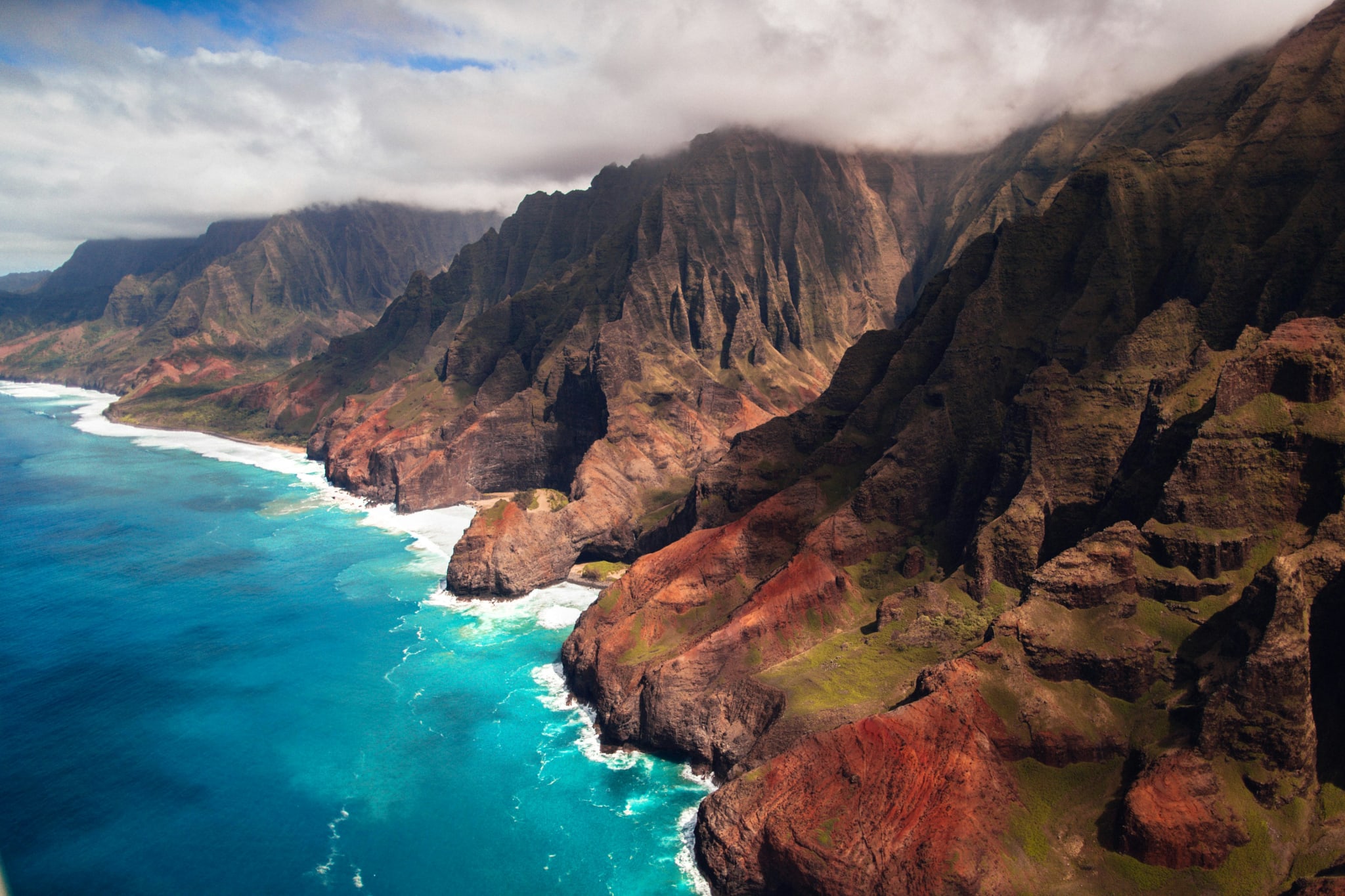 The green, jagged ridges of the Na Pali Coast on Kauai seen from the sea in morning light