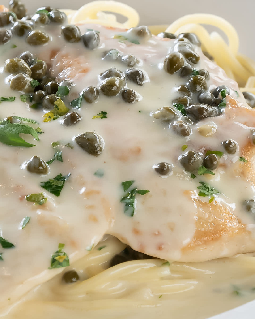 Chicken Piccata over spaghetti topped with capers and a white sauce