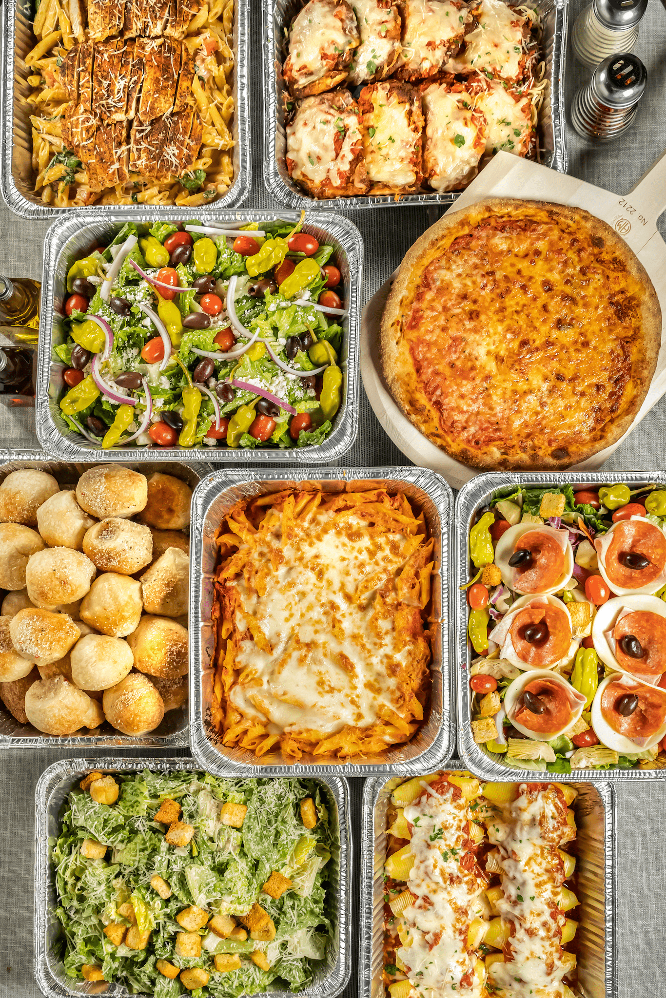 Large table with silver catering trays filled with a variety of food