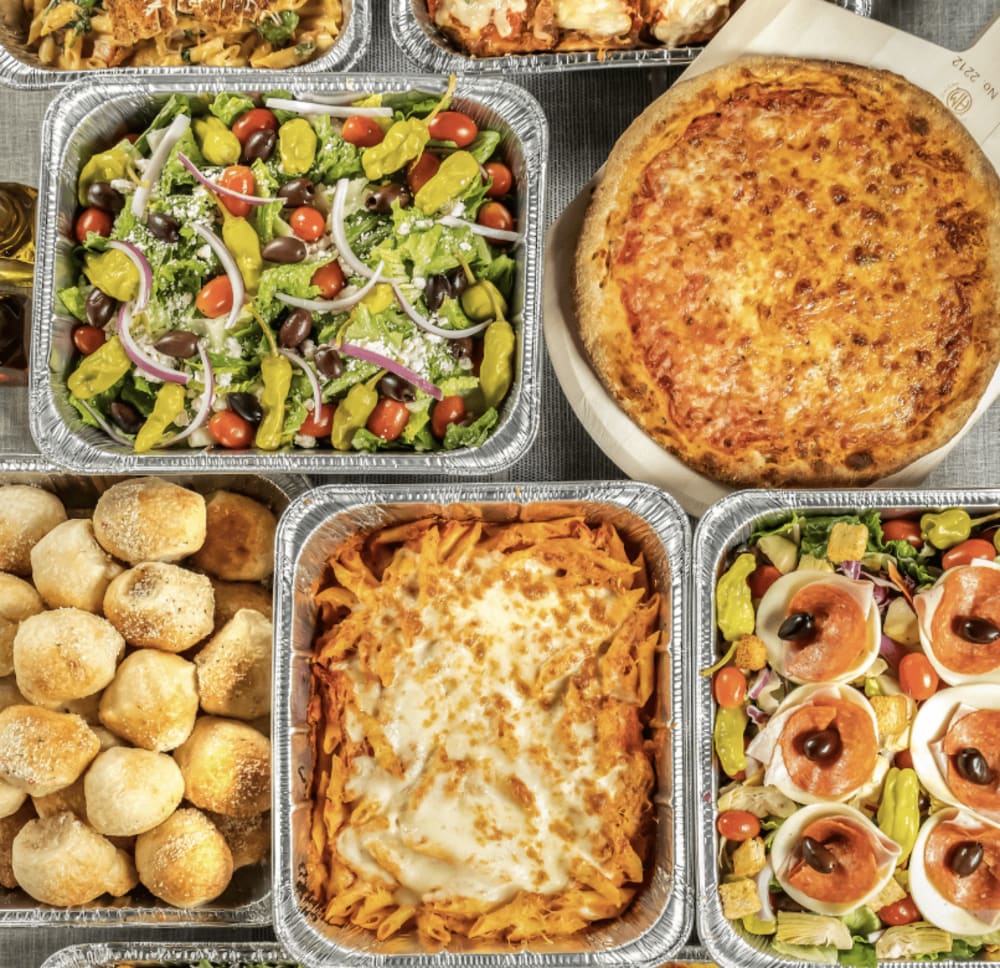 Large table with silver catering trays filled with a variety of food