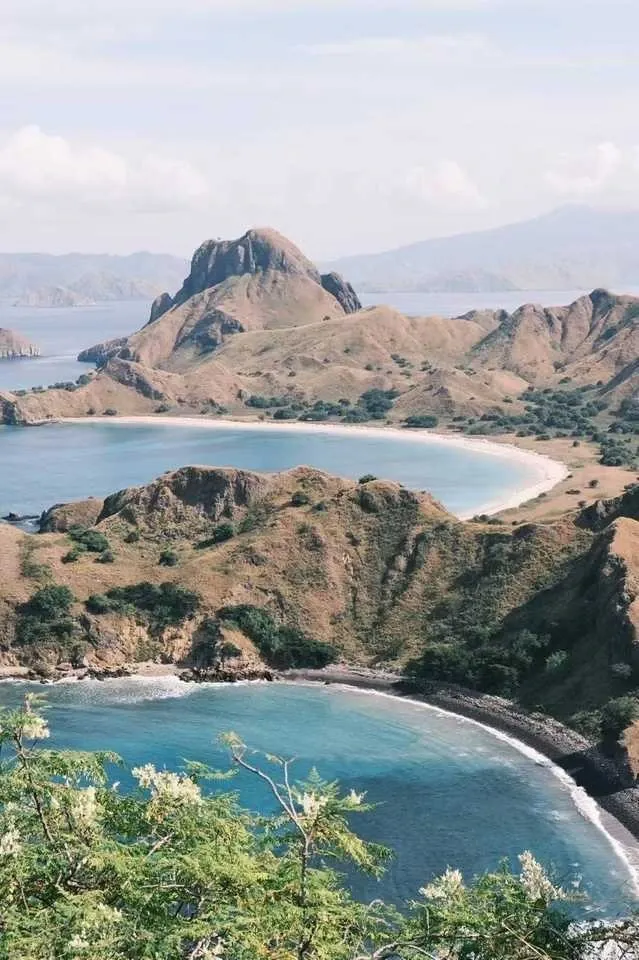 Tourists hiking up Padar Island hill with panoramic scenery