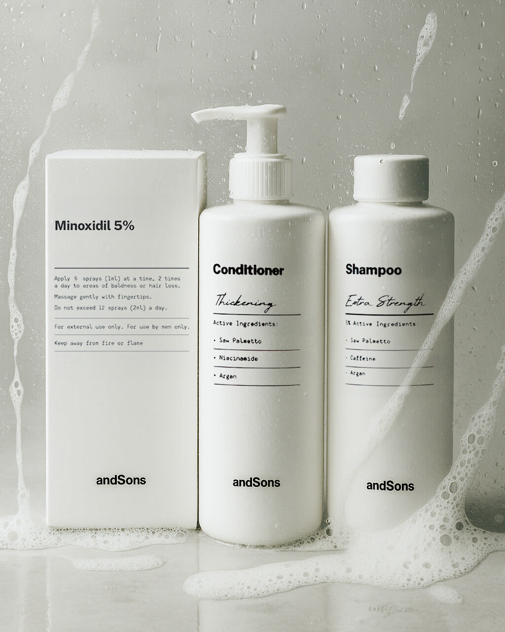 andSons minoxidil box, conditioner and shampoo bottles splashed with foam on pale grey
