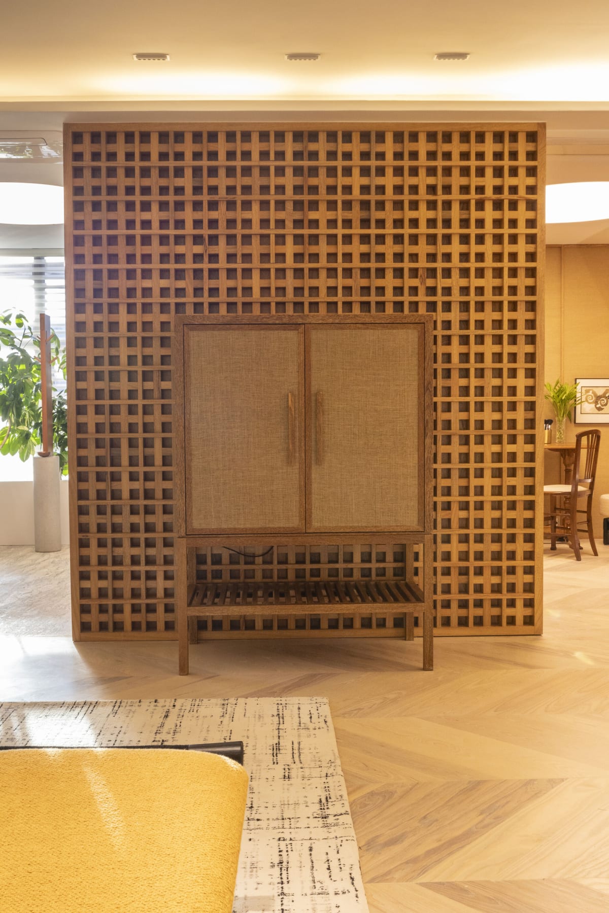 Oak lattice wall framing a cane fronted cabinet on a herringbone floor
