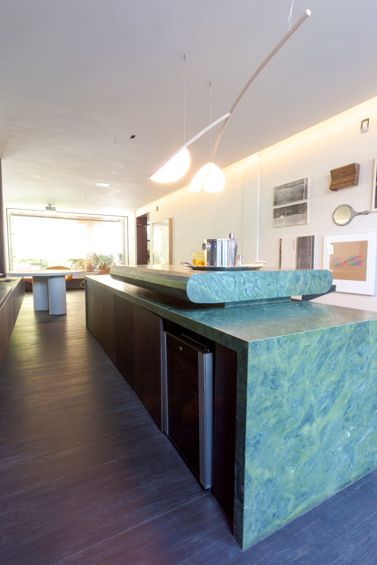 Long green marble bar with a wine fridge under hanging pendant lights