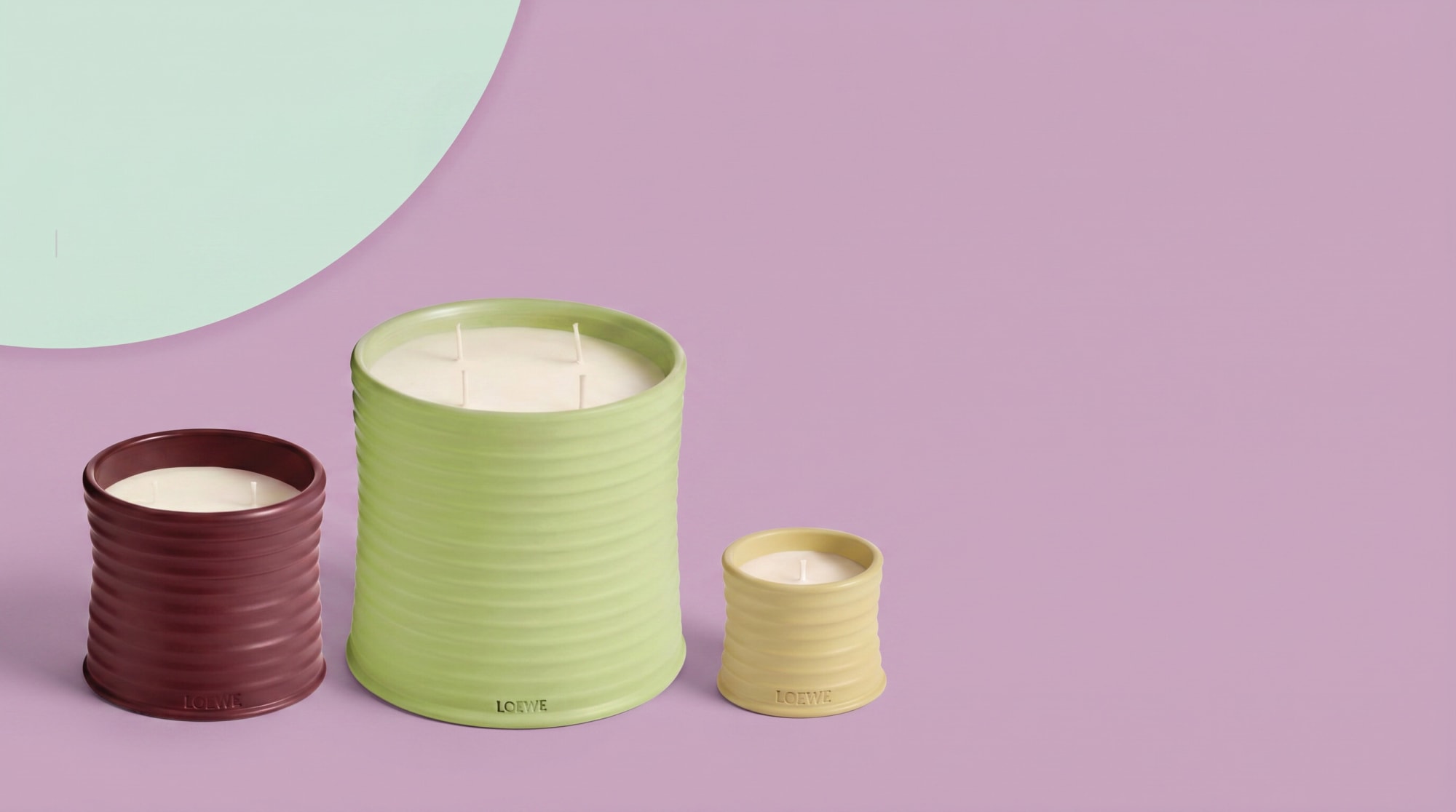 Three ribbed candles in burgundy, lime and cream on a lilac and mint backdrop