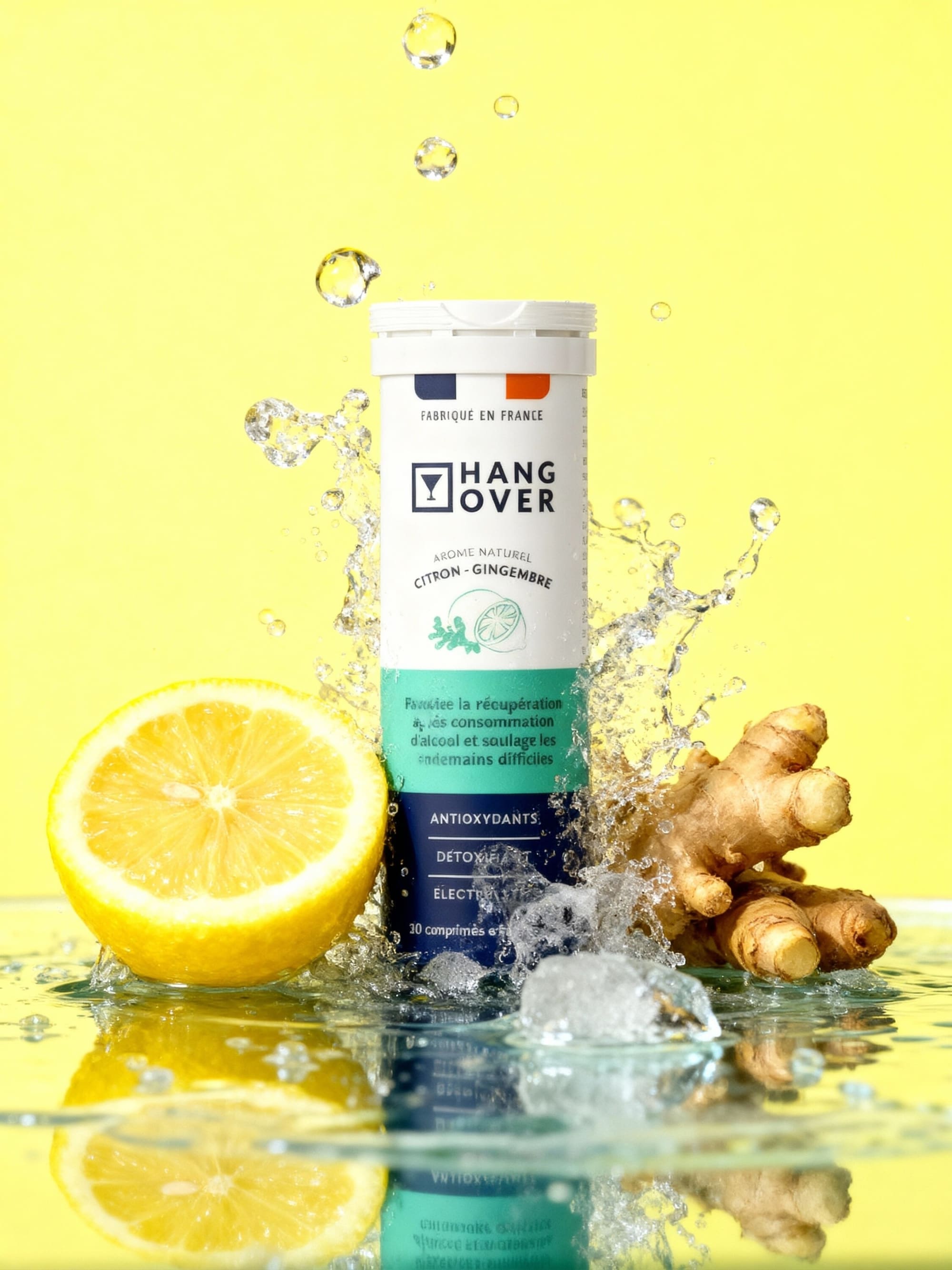 Hangover lemon ginger tube in a water splash with halved lemon and ginger on yellow