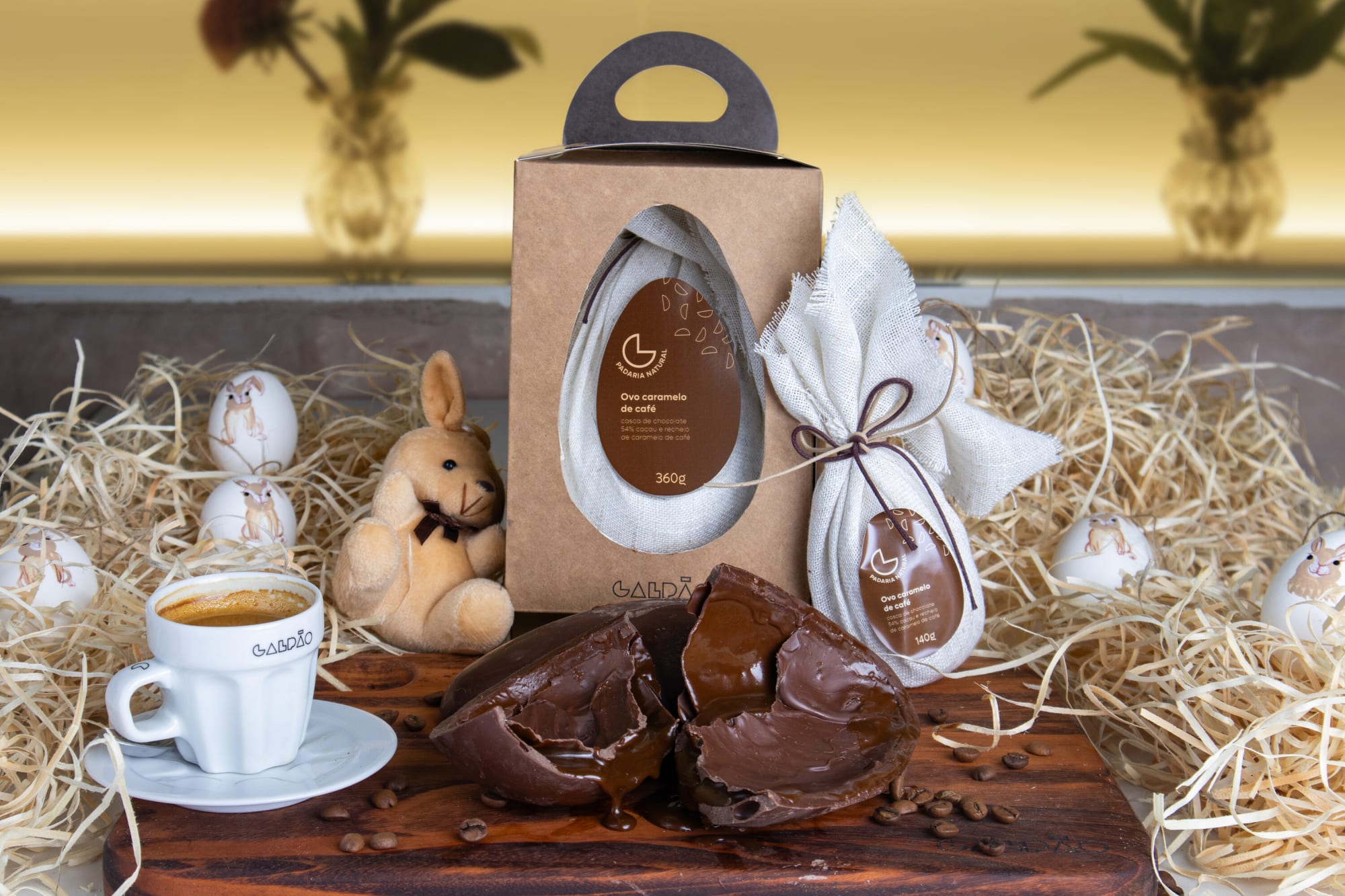 Boxed chocolate Easter egg, broken chocolate shell and espresso on a board in a straw nest