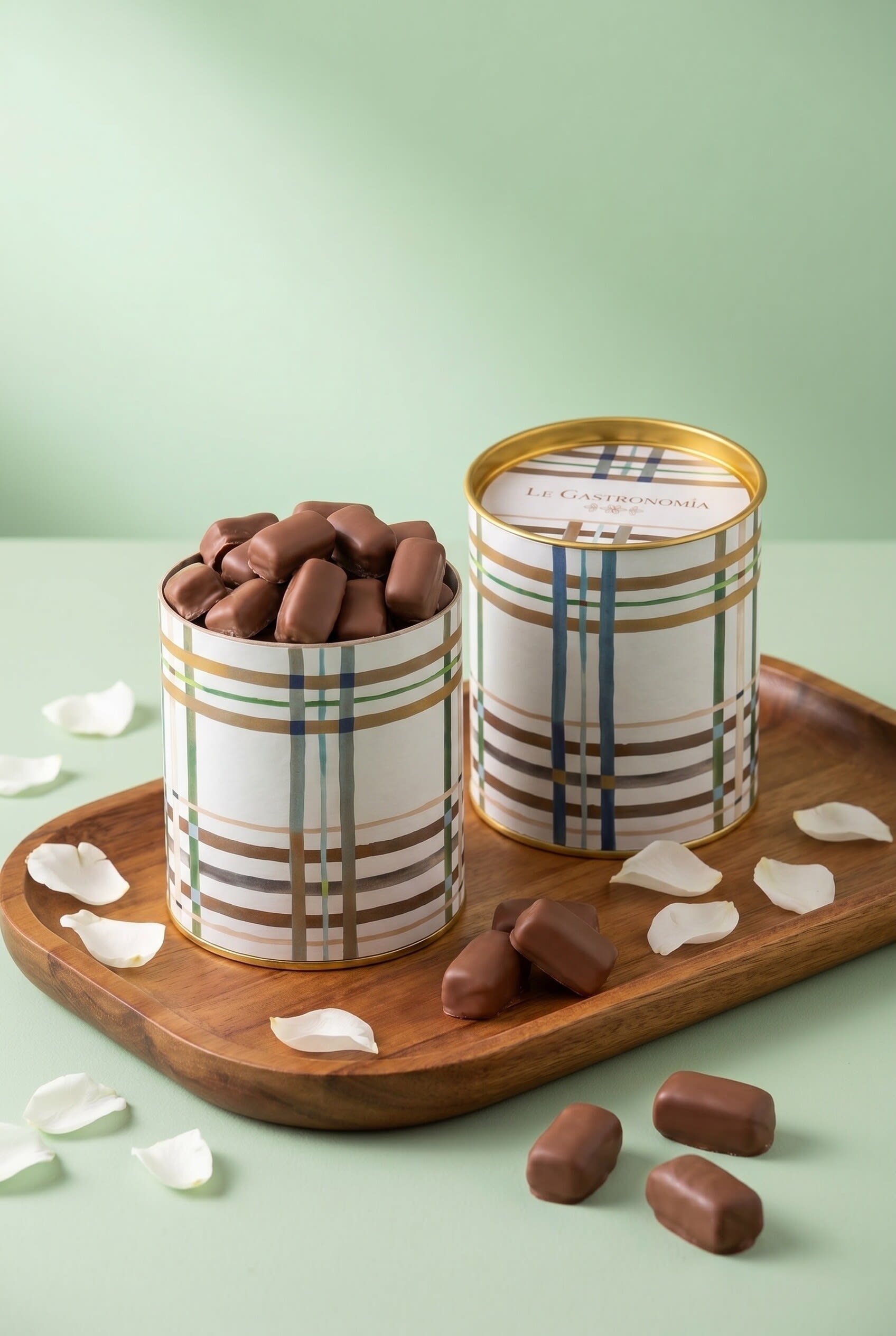 Plaid tins filled with chocolate pieces on a wooden tray with coconut flakes on mint
