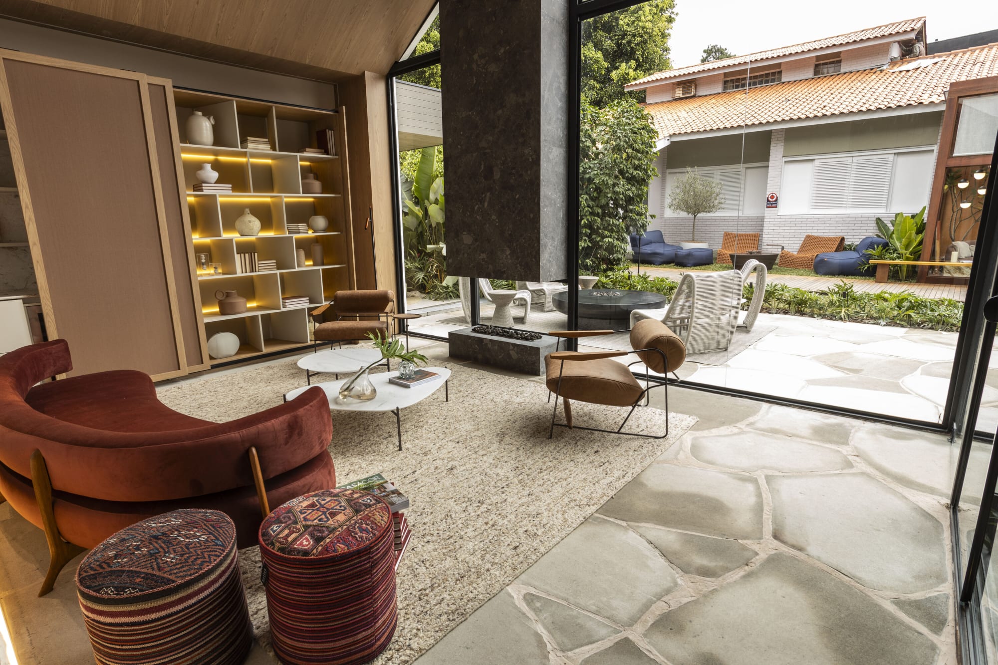 Sala con sillones de piel, repisas iluminadas y un muro de vidrio hacia el patio