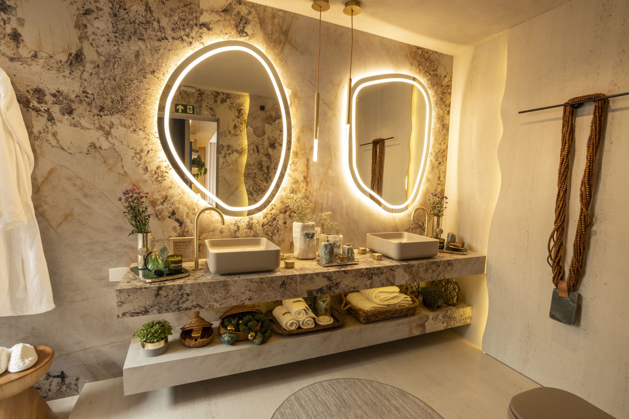 Double vanity with backlit organic mirrors and vessel basins on veined granite