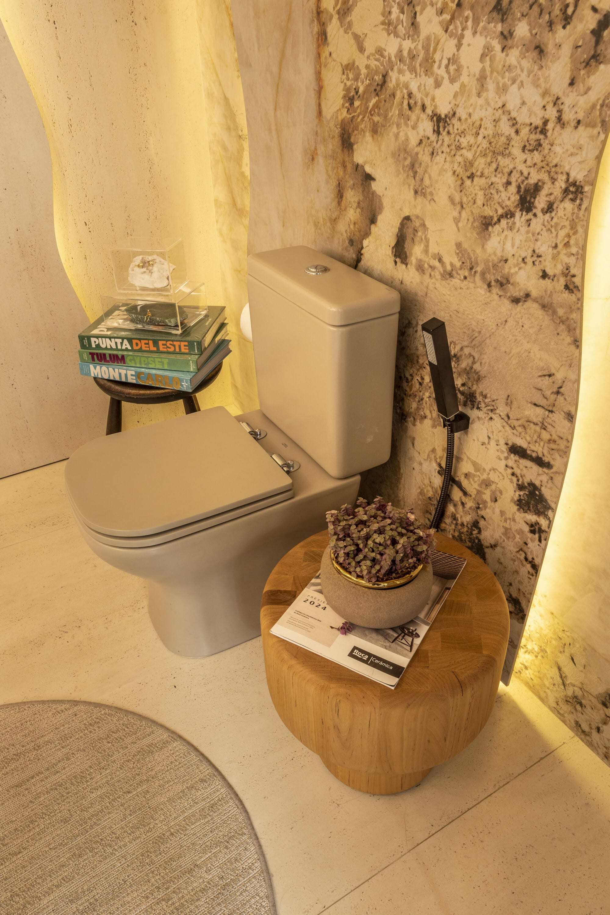 White toilet with books on a wall stool and a carved wooden side table