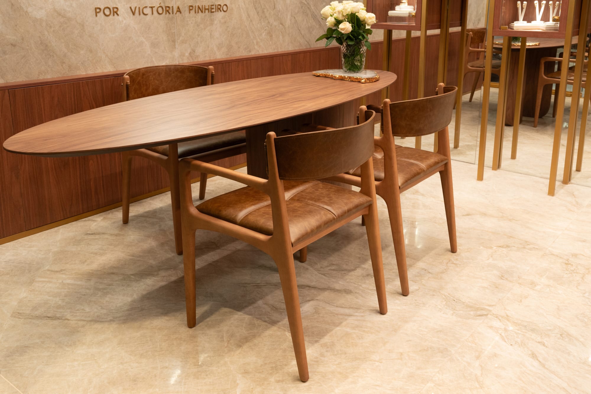 Oval walnut table with leather armchairs in the Victoria Pinheiro jewellery salon at CASACOR Goiania