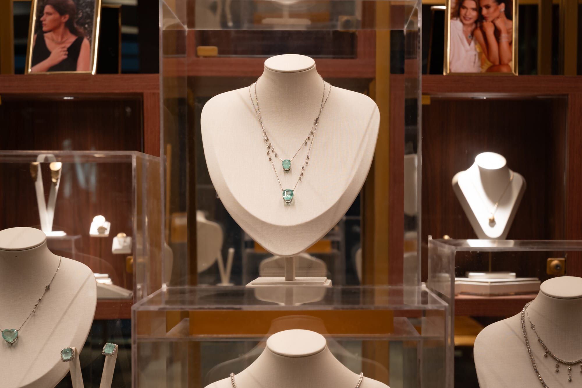 Walnut cabinets lined with jewellery busts and framed portraits in a CASACOR jewellery salon