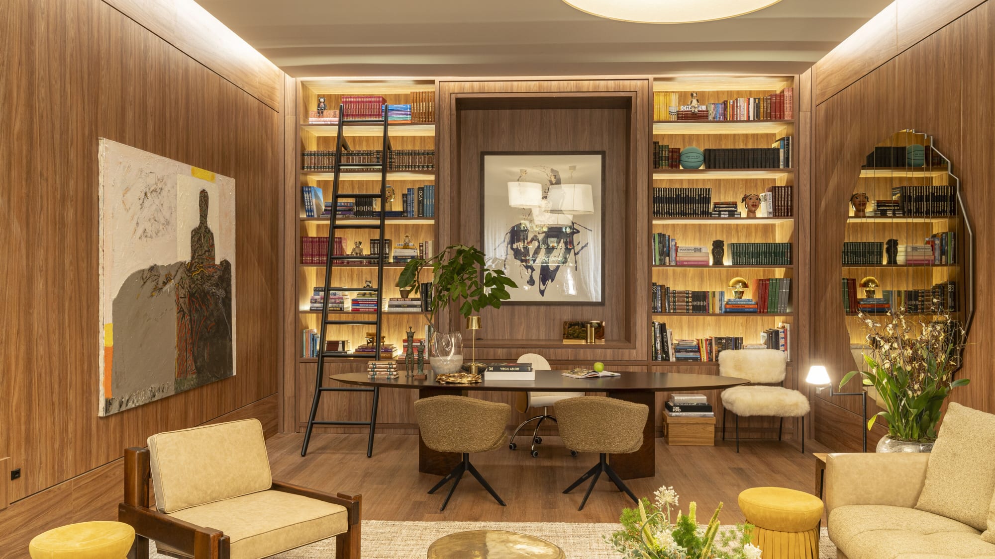 Walnut panelled library living at CASACOR Goiania with lit shelves and a rolling ladder