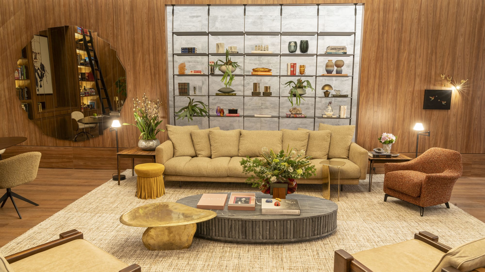Long beige sofa, brass side tables and round coffee tables before a metal display shelf