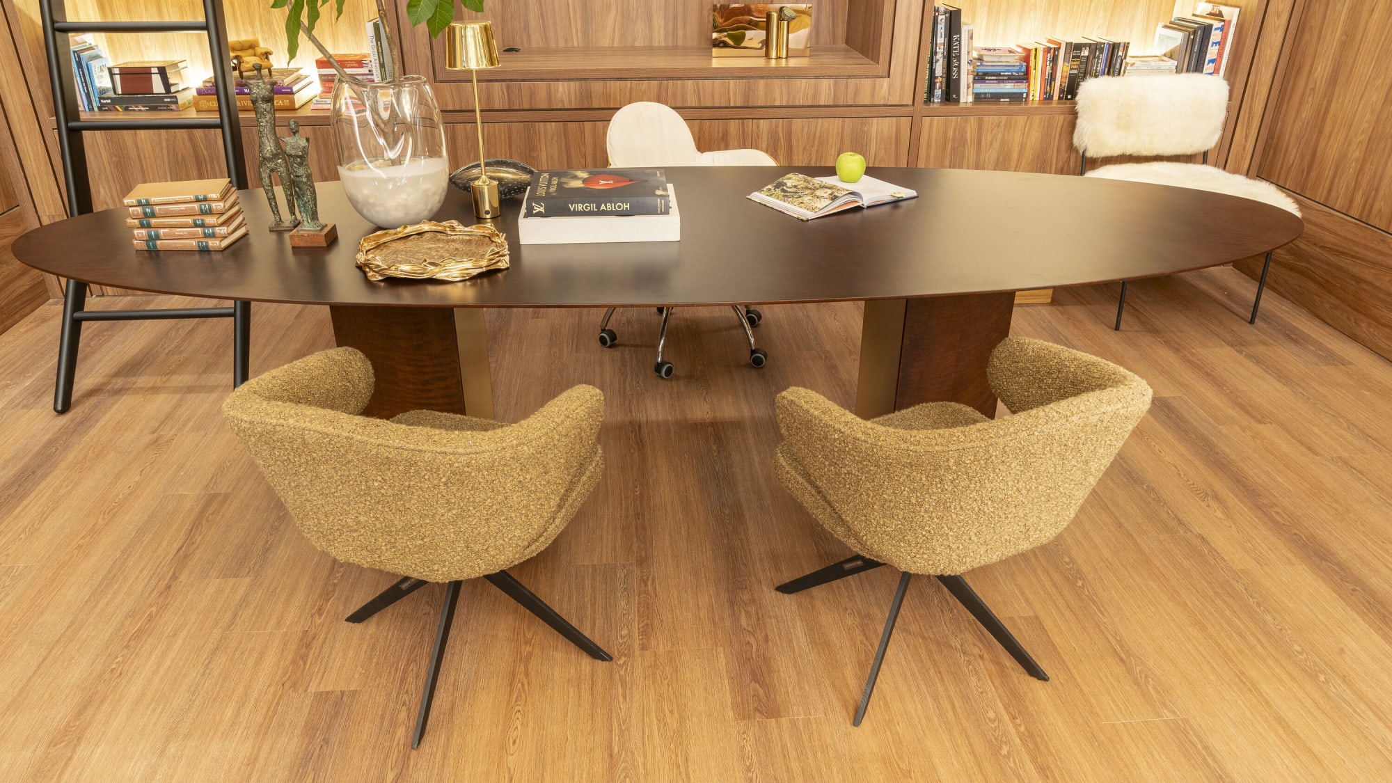 Oval black dining table with four beige bouclé swivel chairs on an oak floor