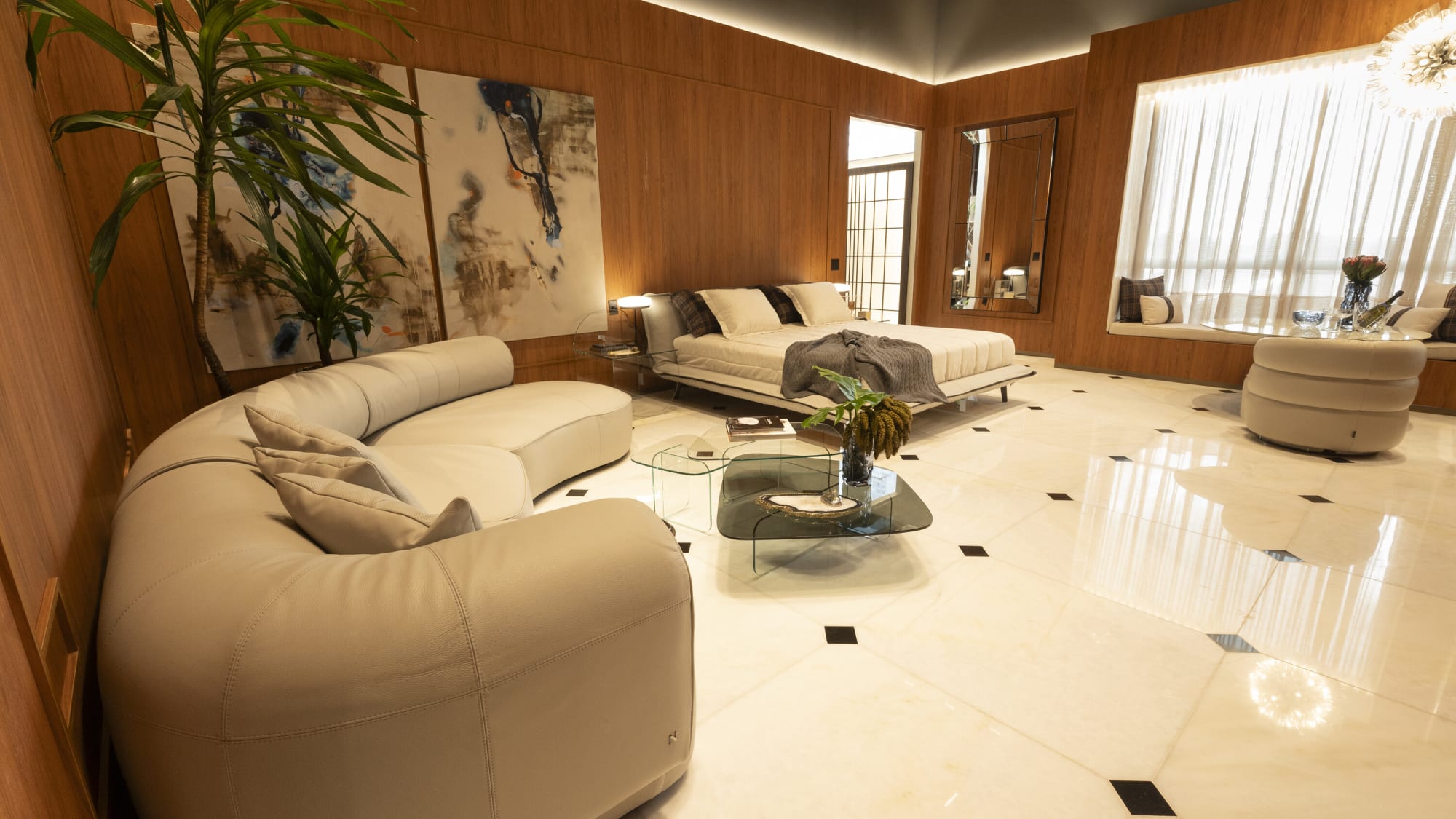 كنبة Natuzzi منحنية تواجه طاولة قهوة من الزجاج المدخّن في جناح مكسو بالجوز