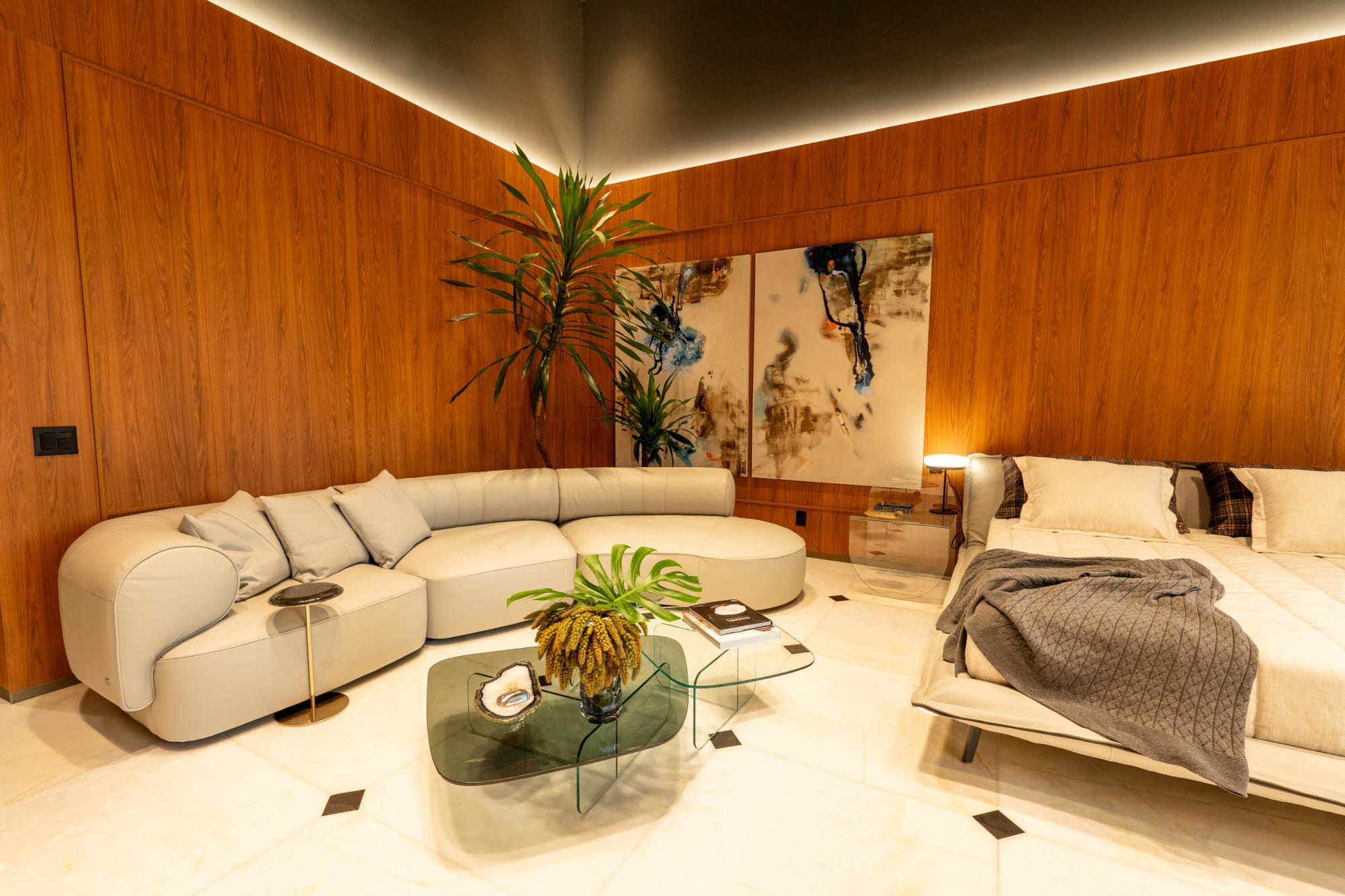 كنبة معيارية كريمية من Natuzzi مع نخلة وعمل فني تجريدي بجانب السرير