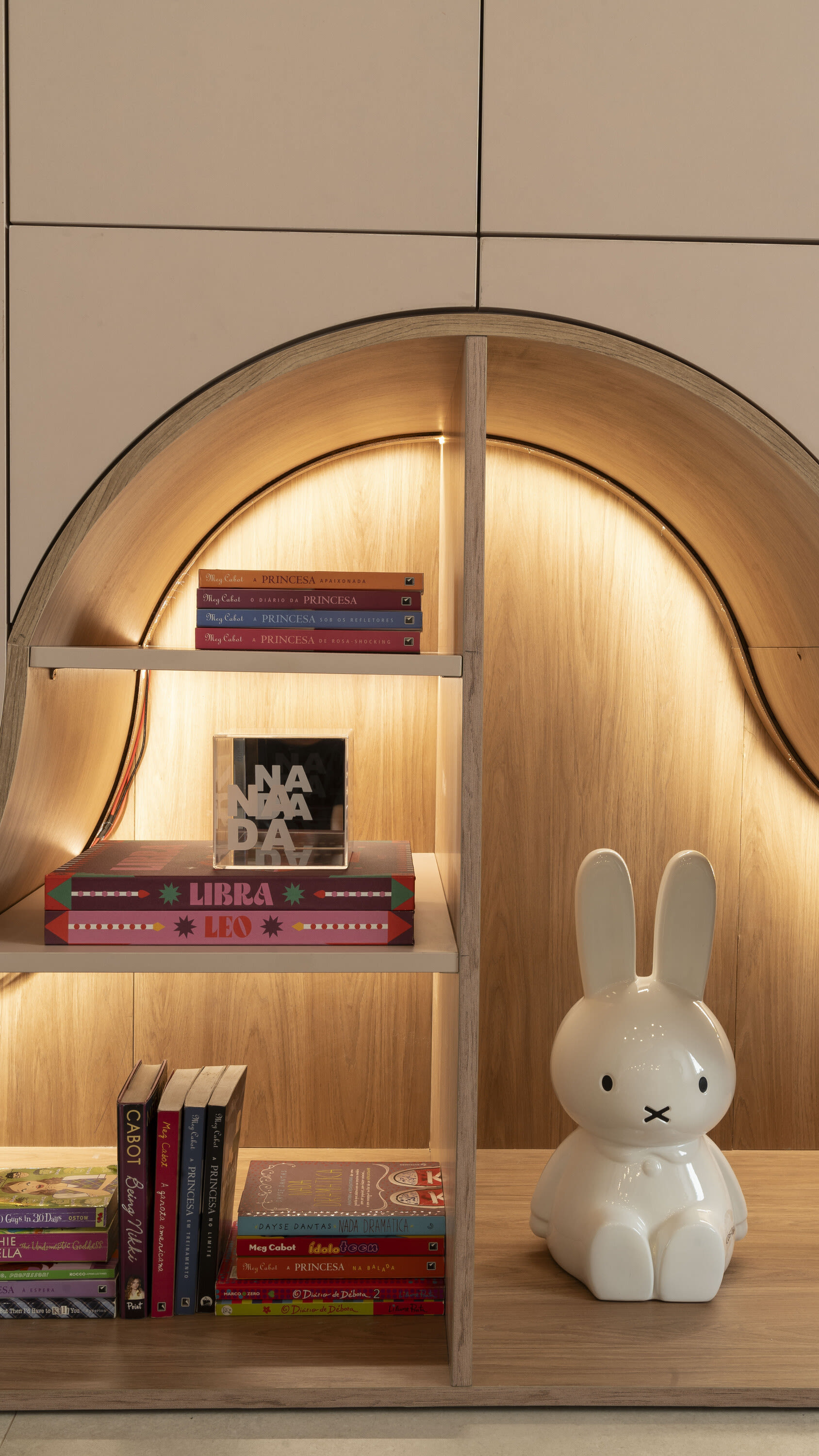 Arched oak bookshelf with children's books and a white bunny lamp