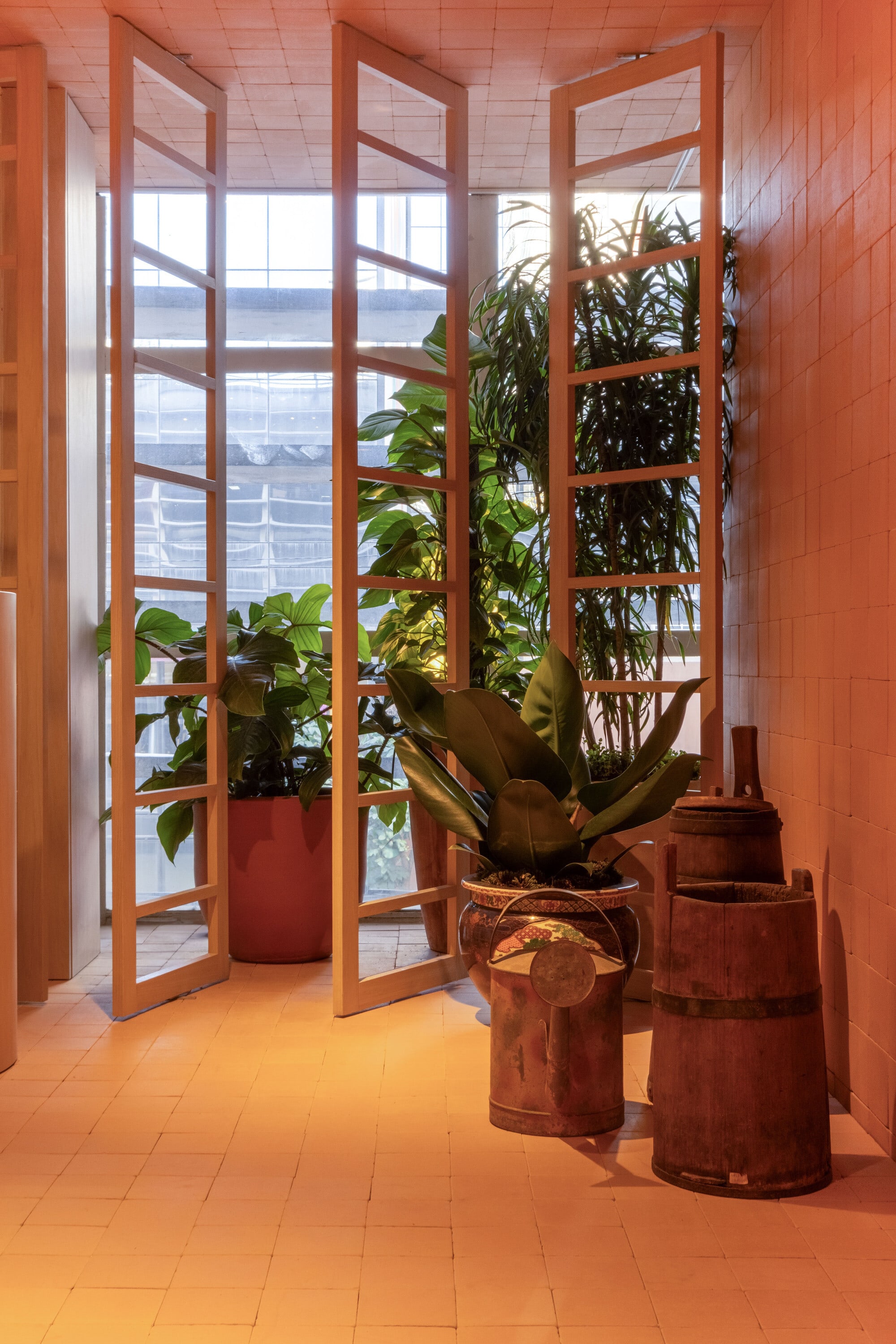 Tall glazed doors with potted plants and antique wooden churns in an ochre entry