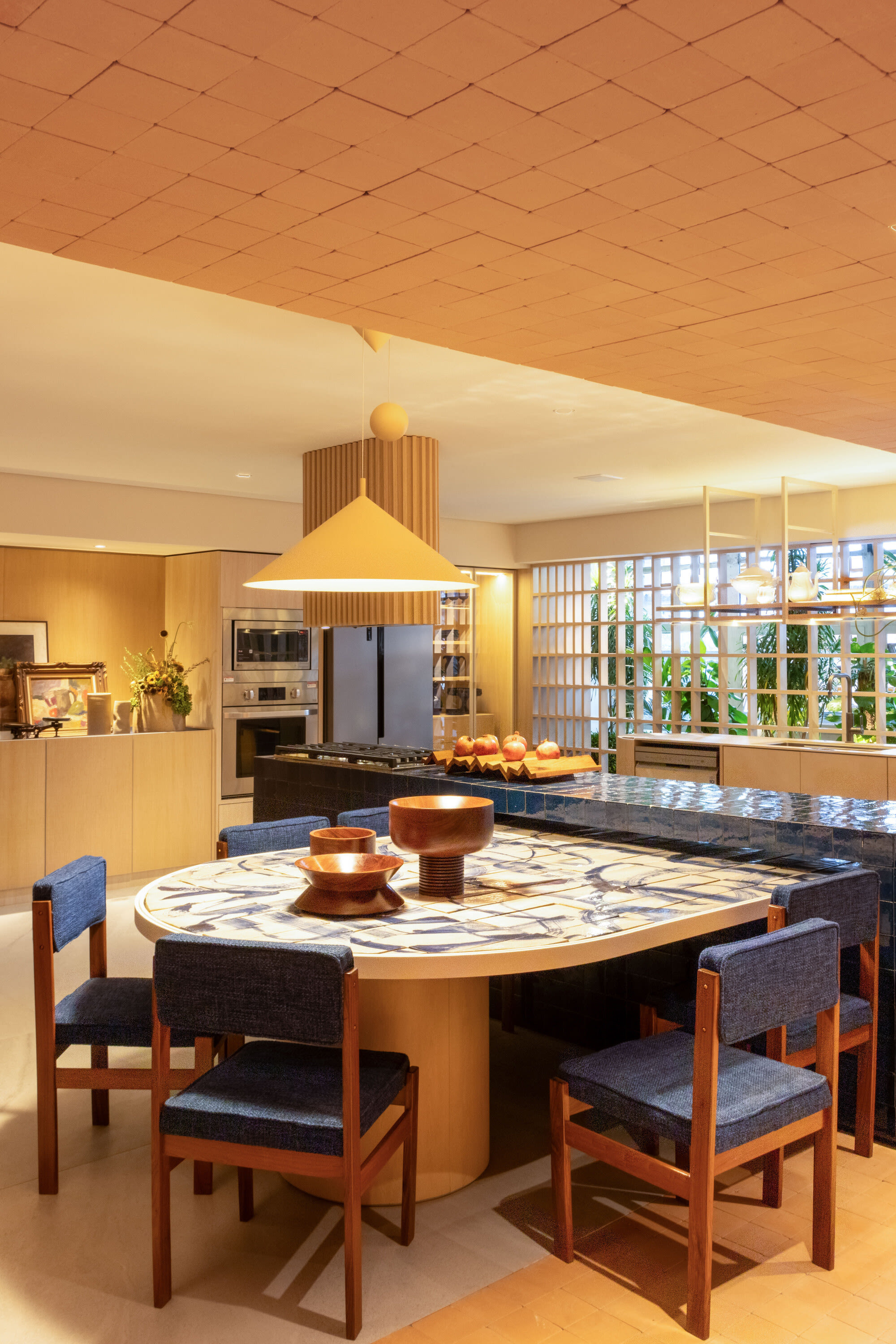 Ochre kitchen at CASACOR São Paulo with a hand painted round table and blue chairs