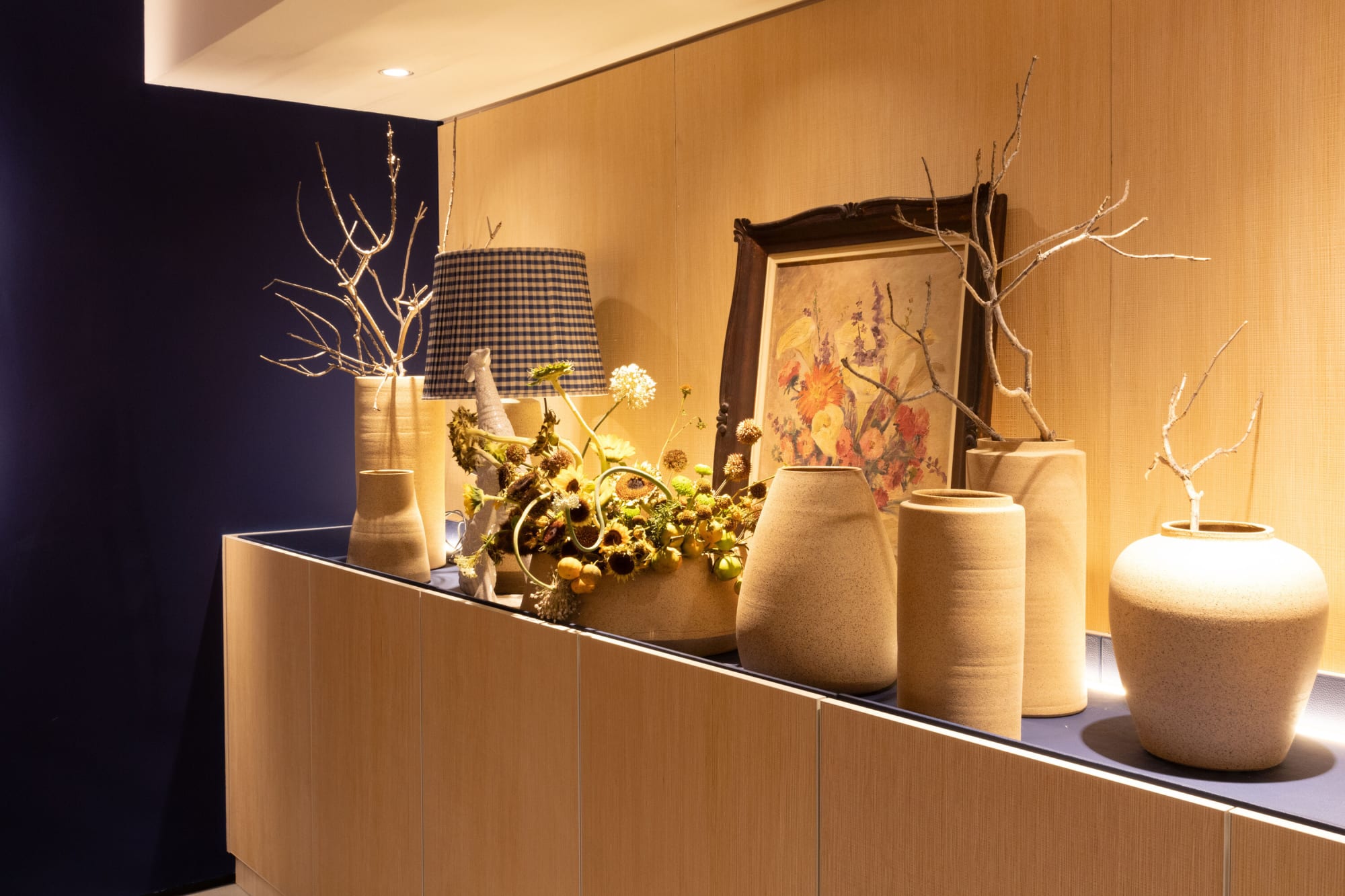 Ceramic vases, dried branches and a framed drawing on an oak sideboard