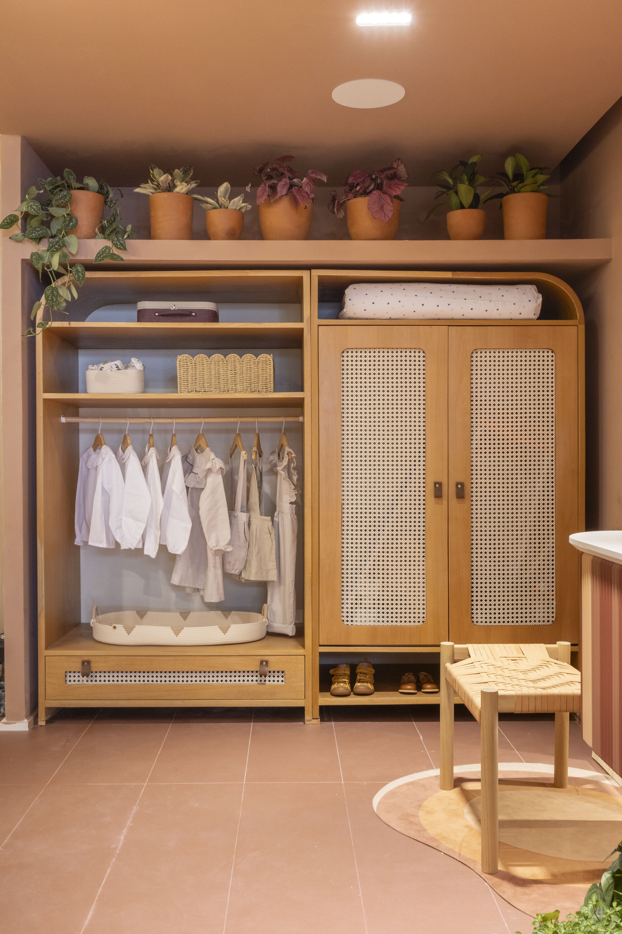 Oak wardrobe with cane doors, small hanging clothes and potted plants above