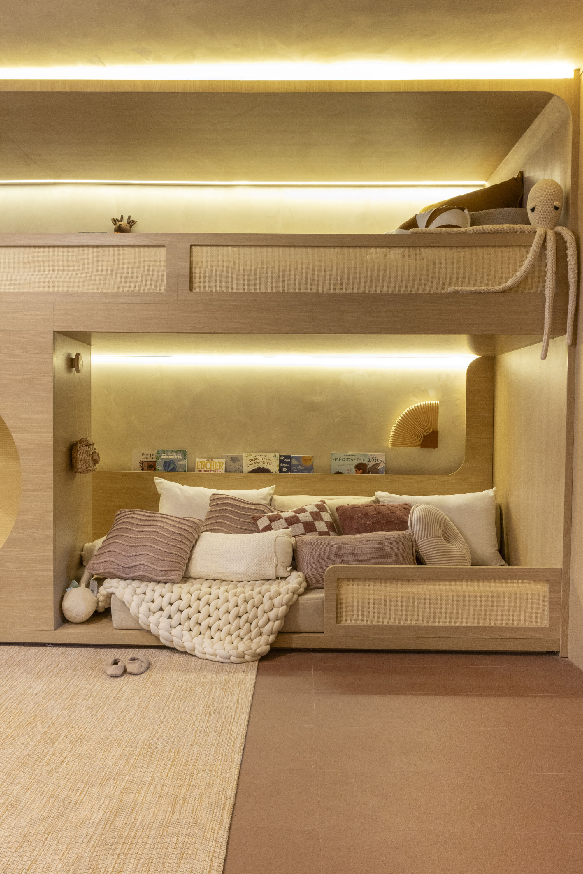 Lit oak bunk niche with cushions, knitted throw and a plush octopus