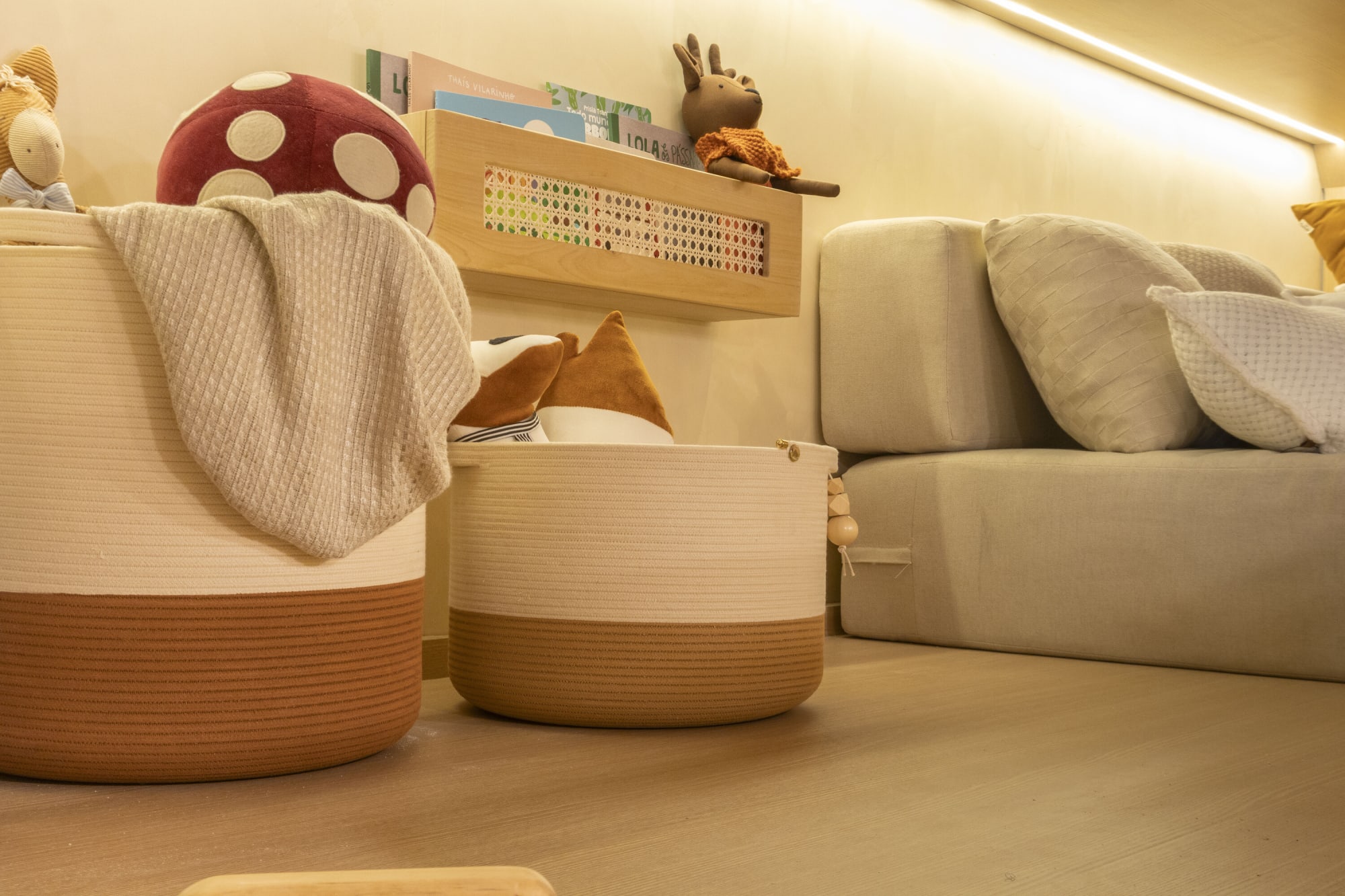 Woven storage baskets, a mushroom cushion and a low sofa in a lit nook
