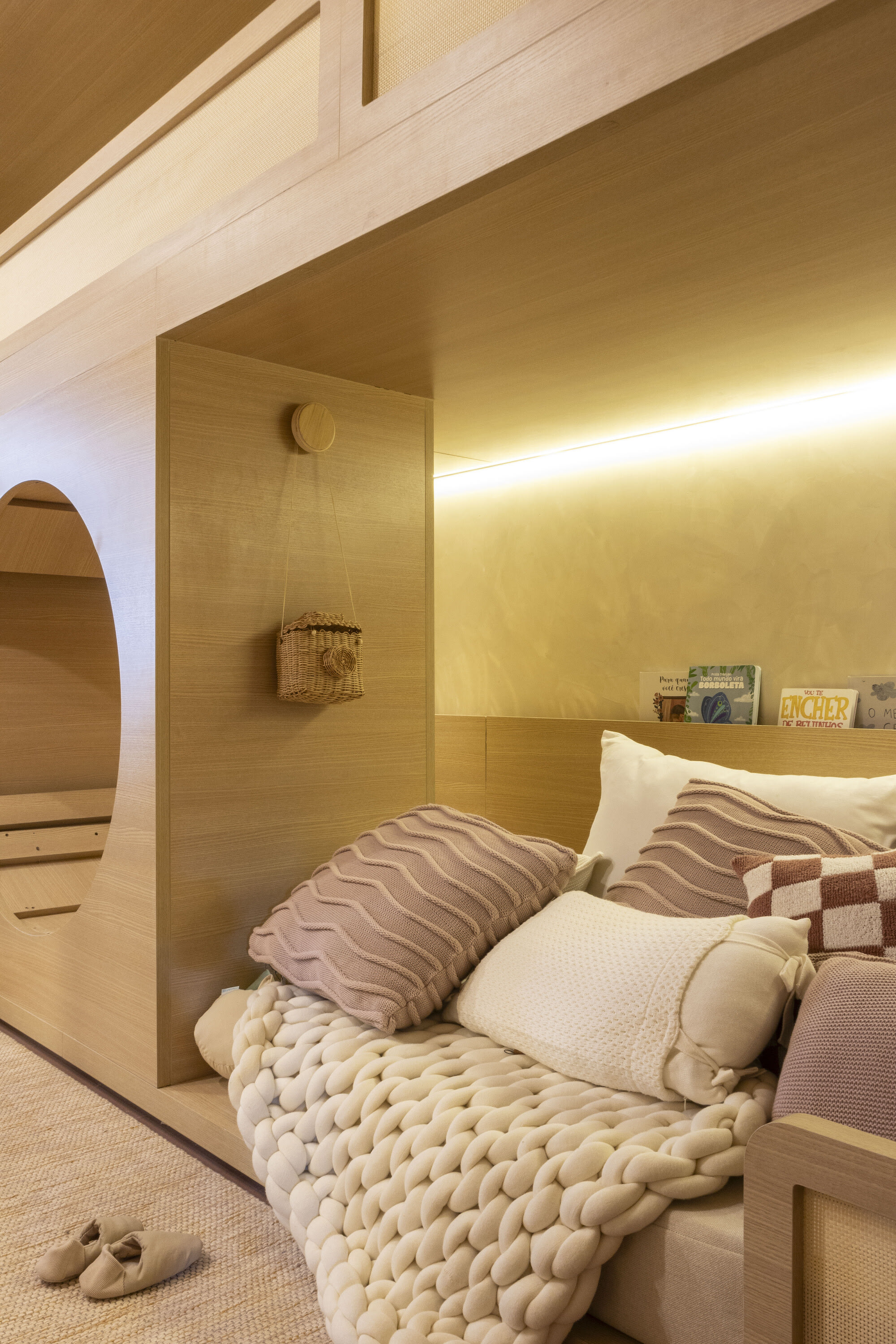 Recessed oak bunk with checked and knitted pillows under a warm strip light