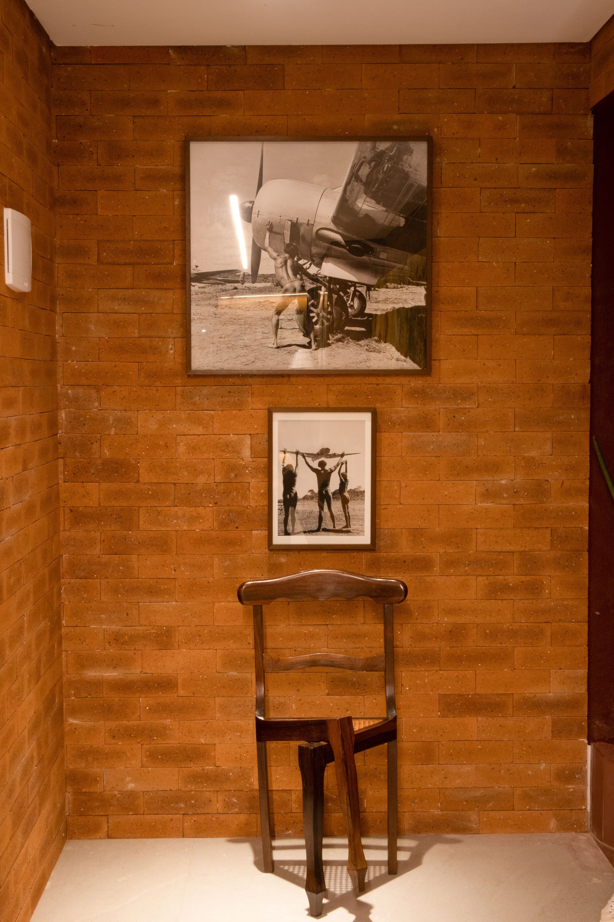 Black and white aviation photographs over an antique wooden chair on a brick wall
