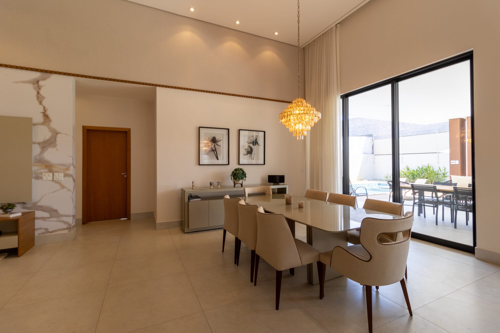 Dining room with long table, upholstered chairs and gold pendant
