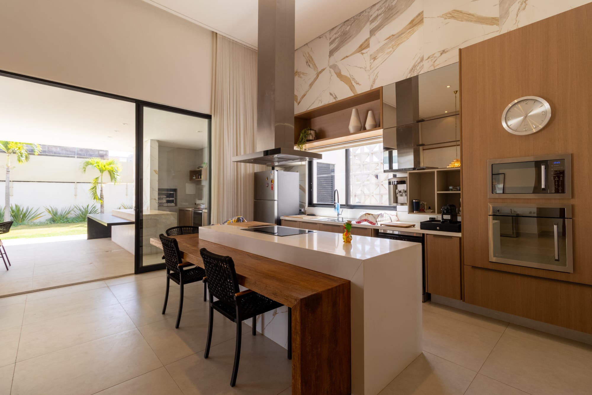 Kitchen island with timber bar, built in ovens and glass door to the garden