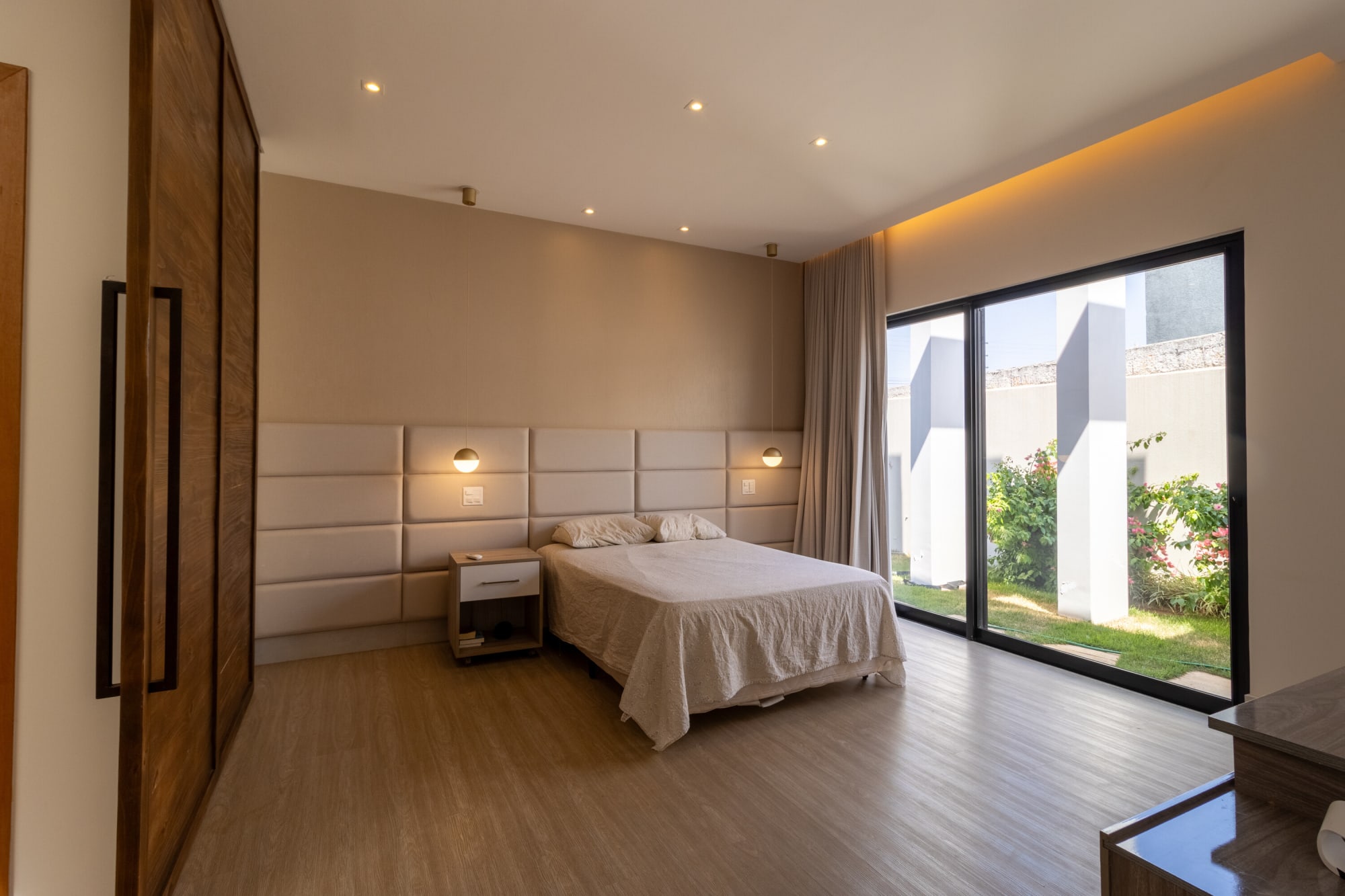Bedroom with padded headboard wall, warm cove light and glass door