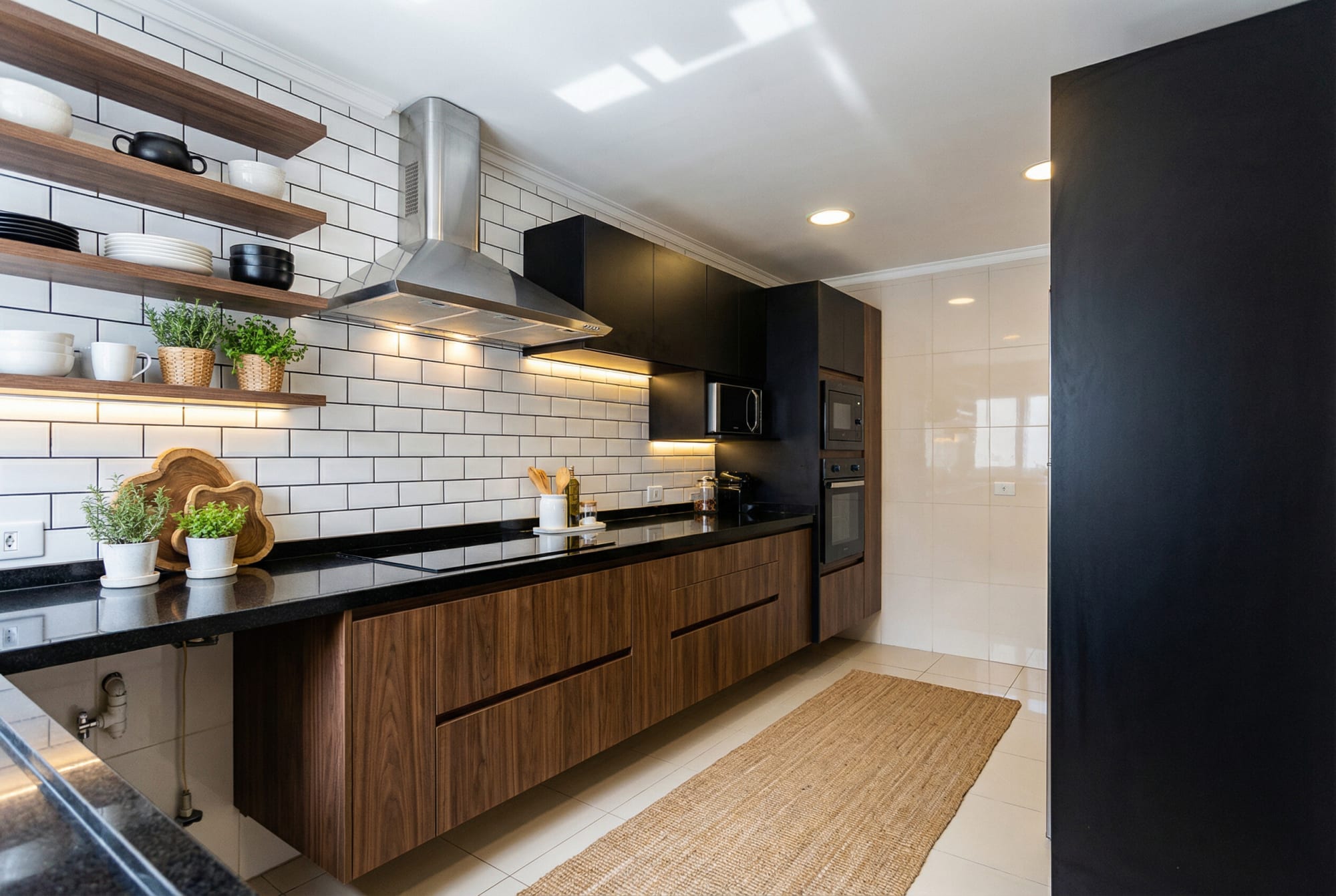 Kitchen with walnut cabinets, black counter and white subway tile shelves