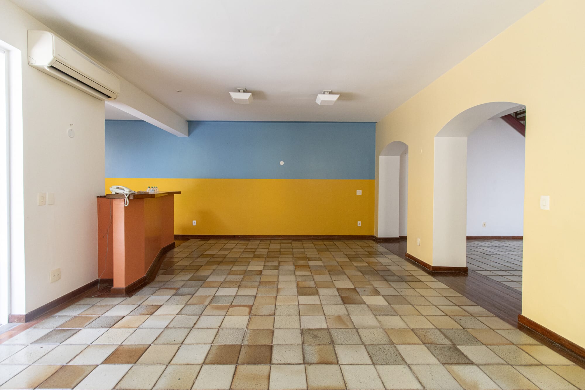Empty room with blue over yellow colour block walls and arched doorway